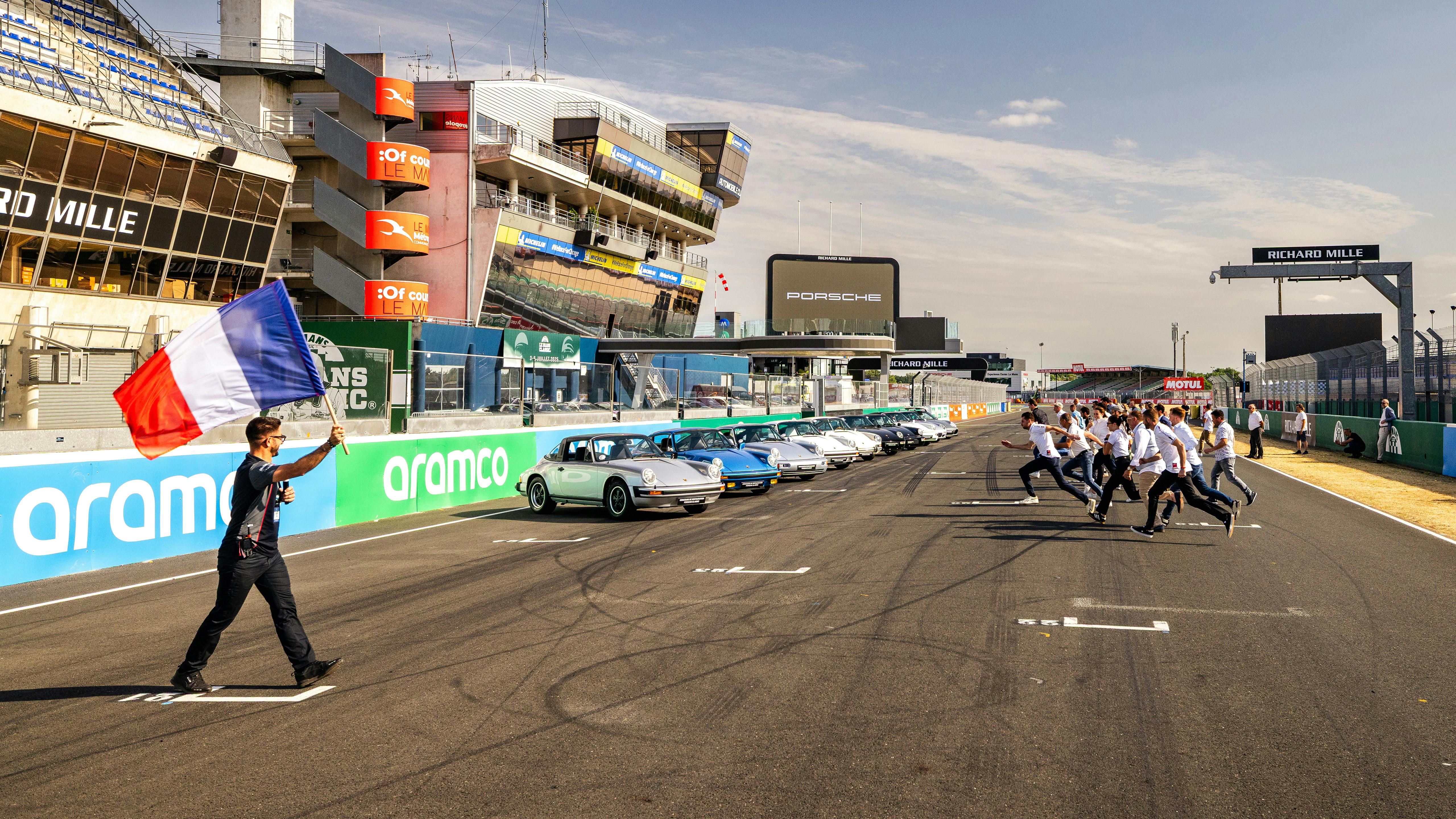 Participant courant vers leur véhicule sur la ligne de départ arrivée du circuit du Mans