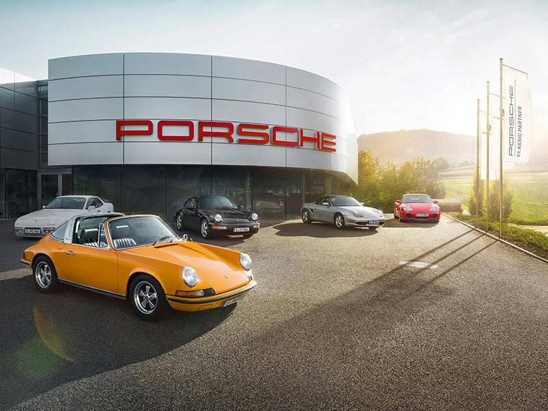 Porsche Classic Partner, Red logo on the building, various Porsche models in the front car park.