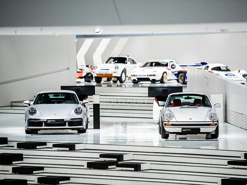 Weitläufiger weißer Raum mit ausgestellten Porsche Fahrzeugen