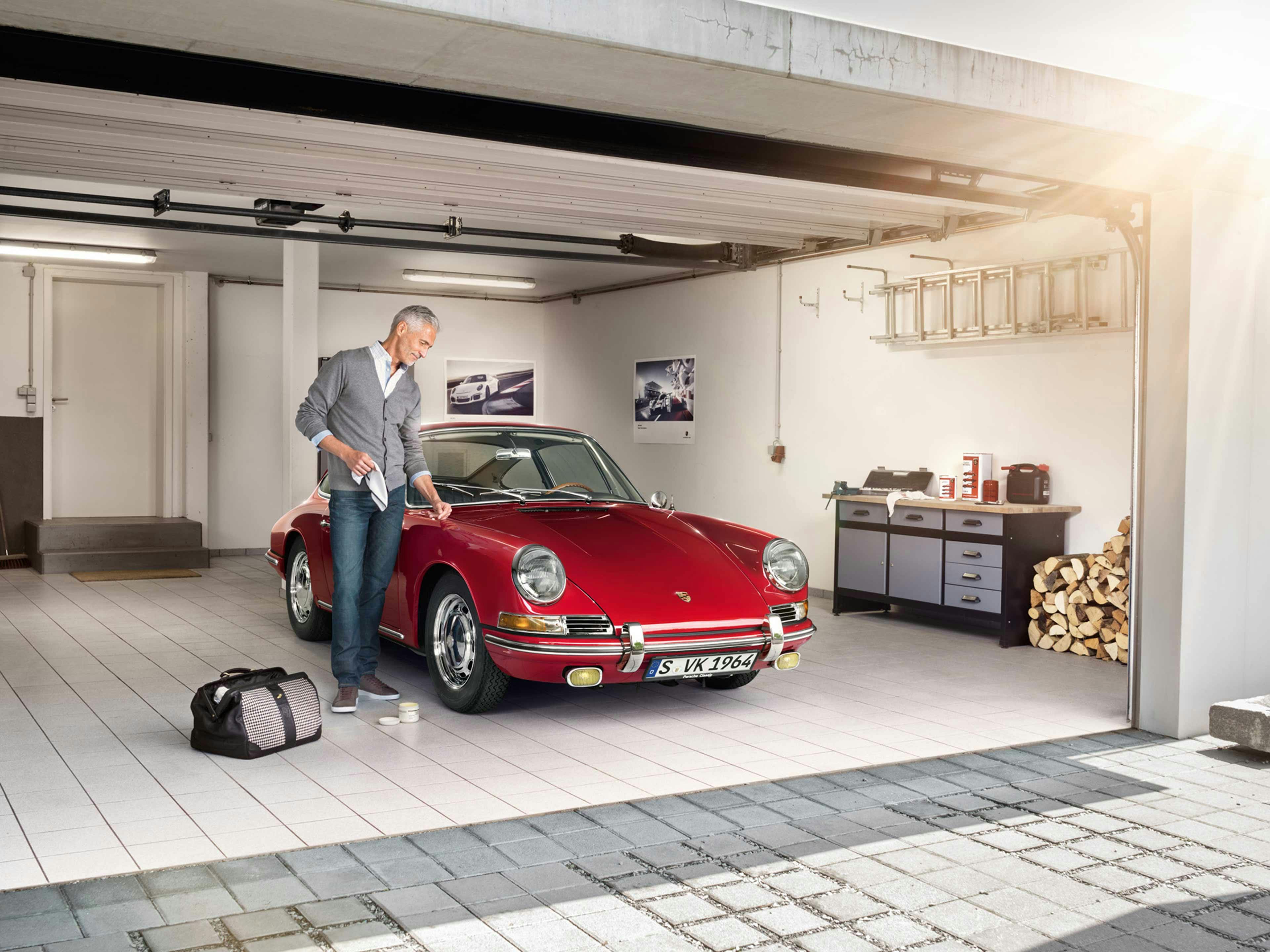 Garage view: Porsche Classic, man cleans a Red Porsche vintage car with a cloth.