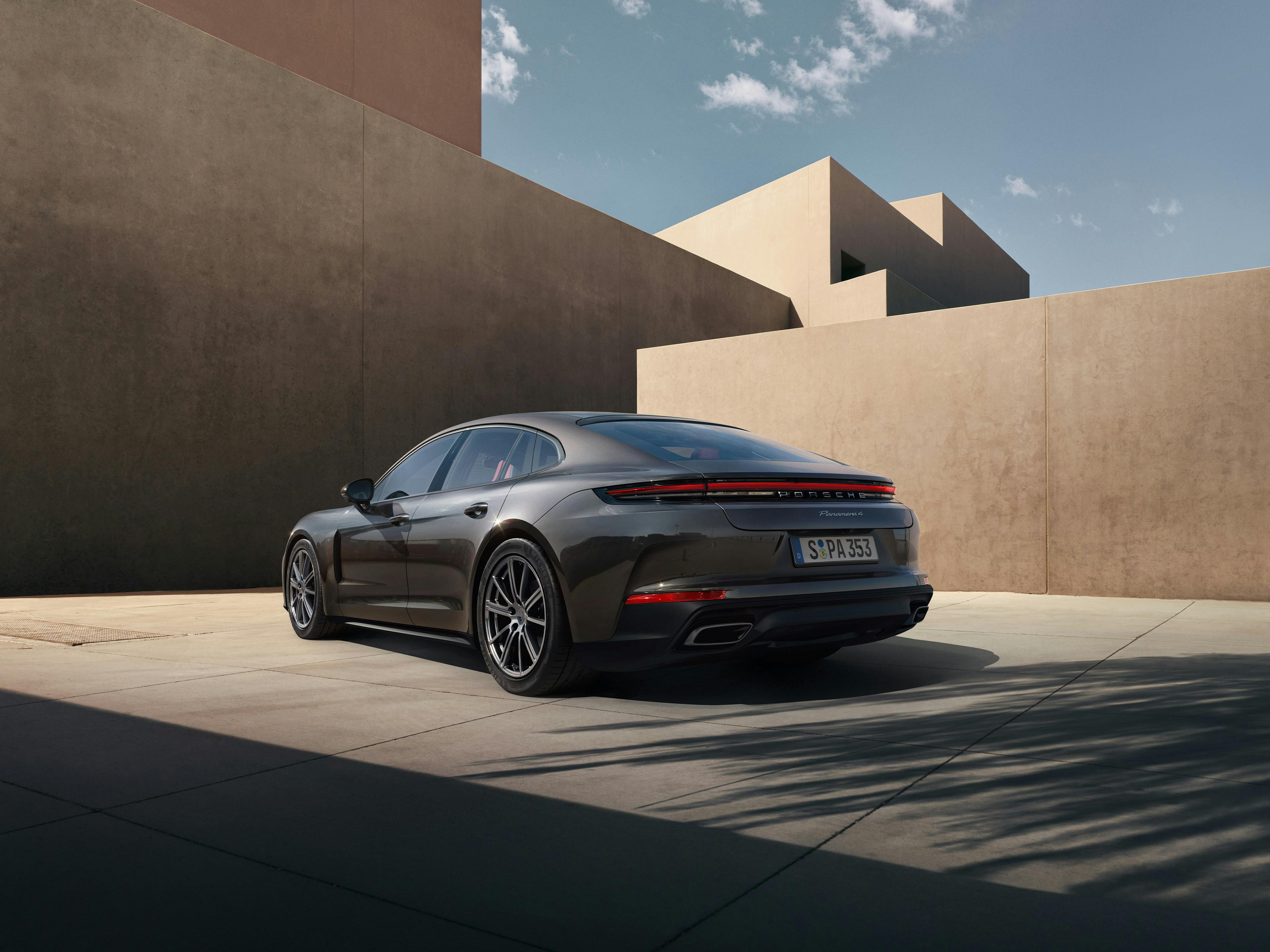 Ein grauer Panamera 4 parkt mit dem Heck zur Kamera vor einem modernem Gebäude.