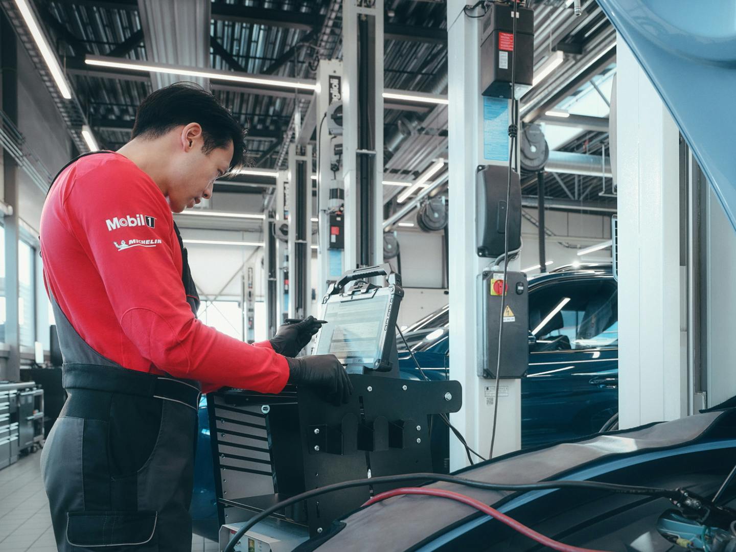 A workshop employee looking at the screen of the computer connected to a Porsche Taycan.