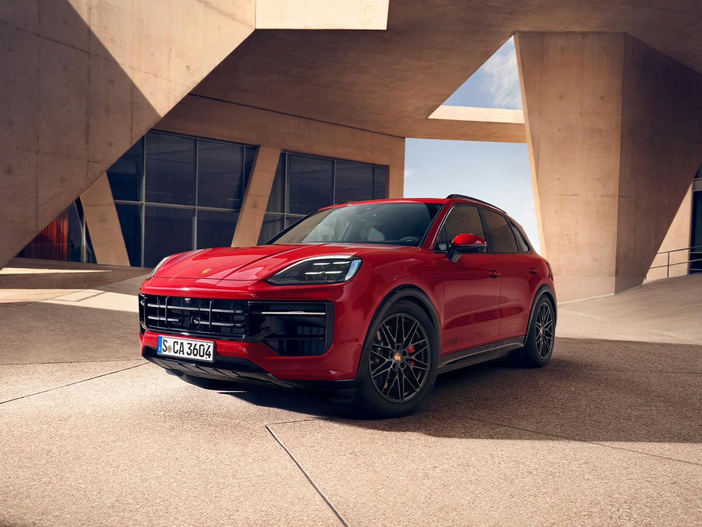 Roter Porsche Cayenne GTS vor moderner Architektur, mit sportlichem Design und markanten schwarzen Akzenten.
