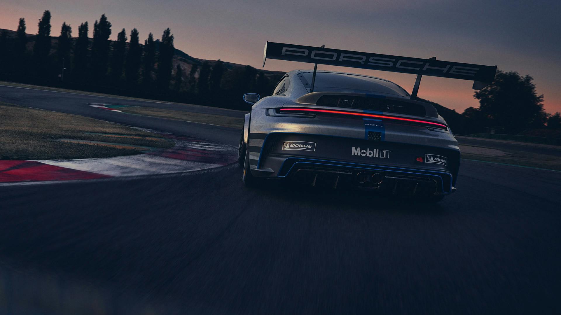 A Porsche 911 on a racetrack at sunset. The licence plate reads Mobil 1.