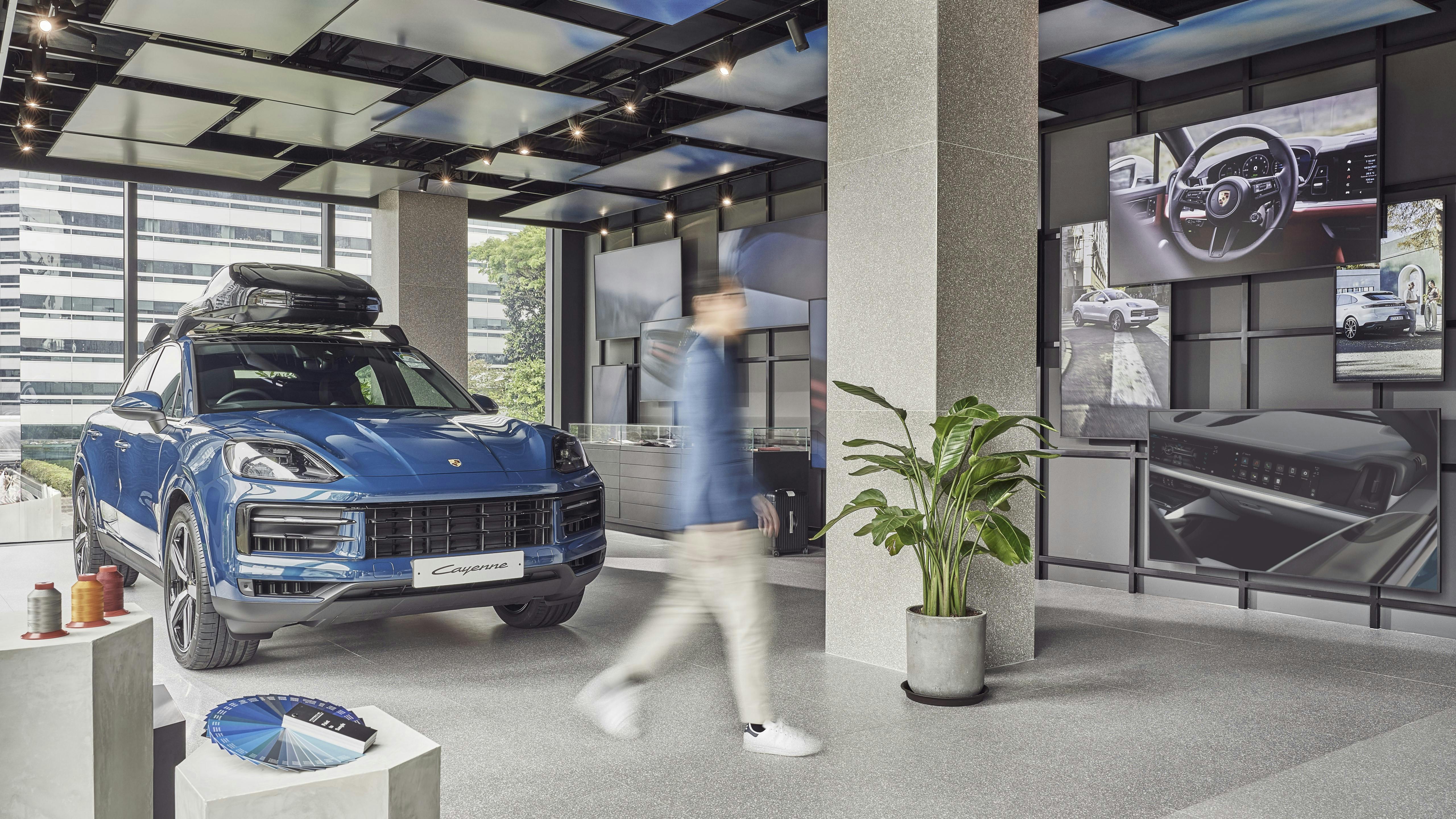 Exhibit area at Porsche Studio Singapore with a blue Porsche Cayenne Coupe on display.