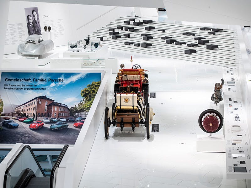 Weitläufiger weißer Raum mit historischem Porsche Fahrzeug