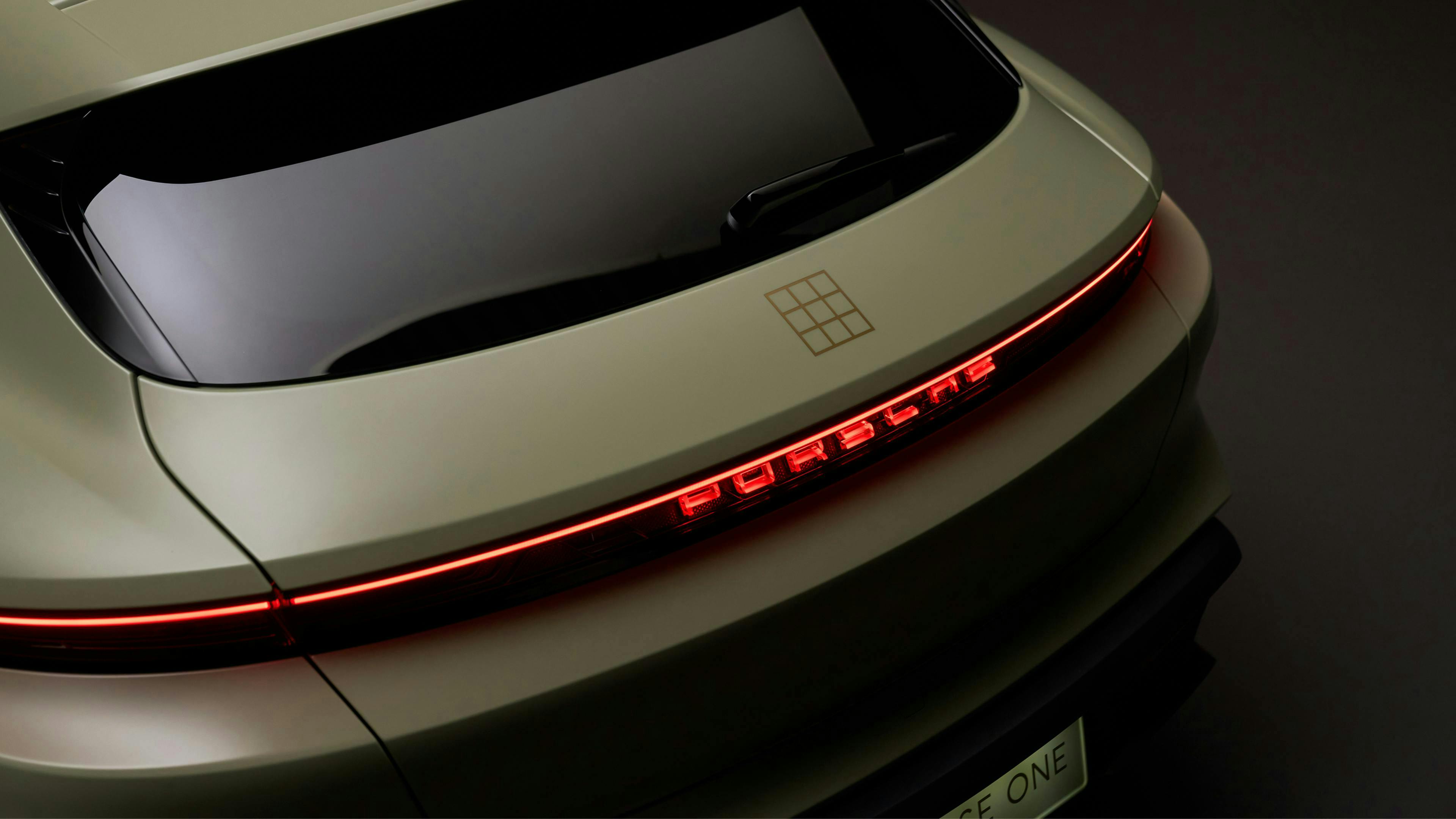 Rear detail of the Taycan Turbo S Soho House One, showing the illuminated Porsche light bar, the Soho House logo and the brass coach line on satin green bodywork.