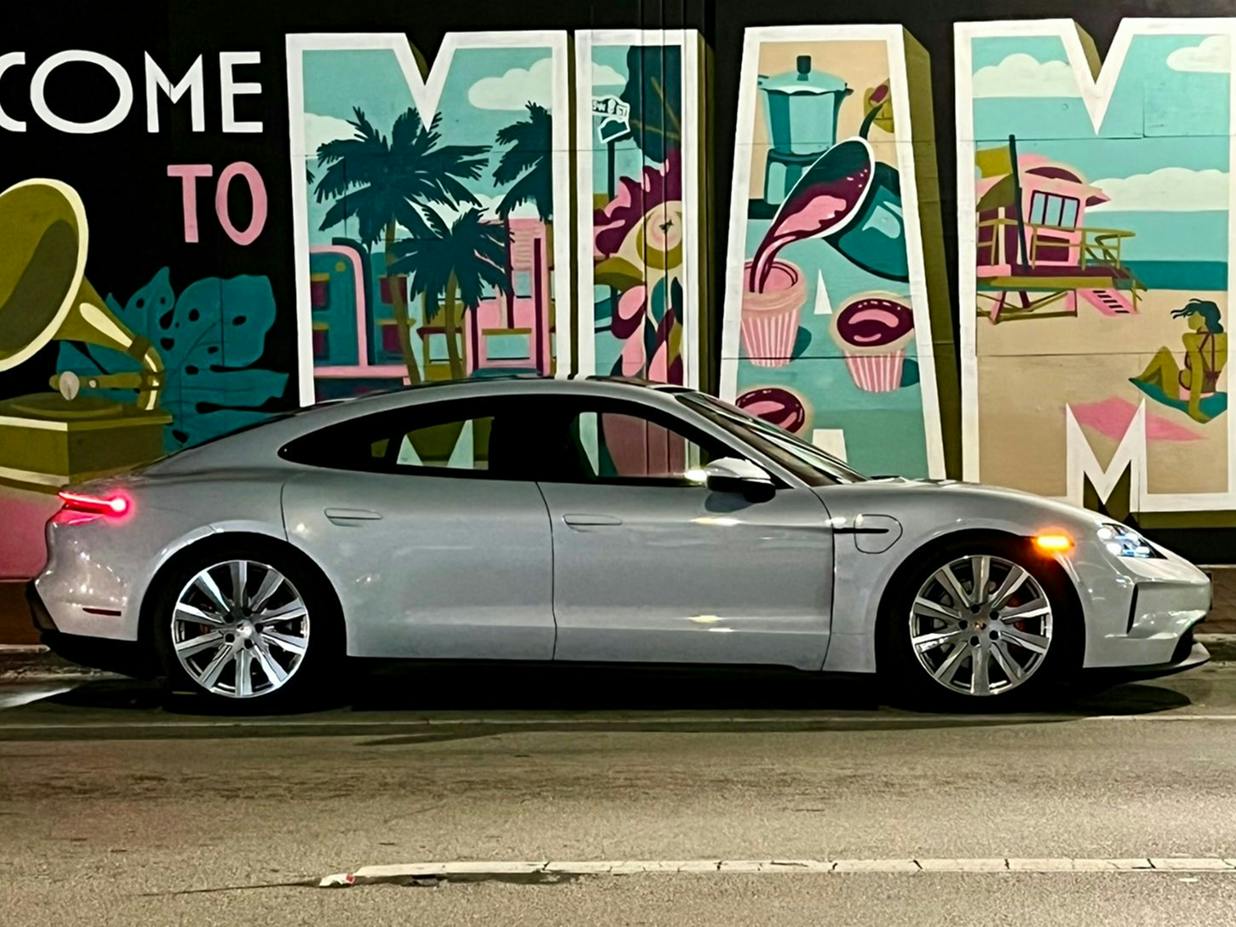 Um Porsche Taycan em frente a um graffiti colorido. Vista lateral do veículo.