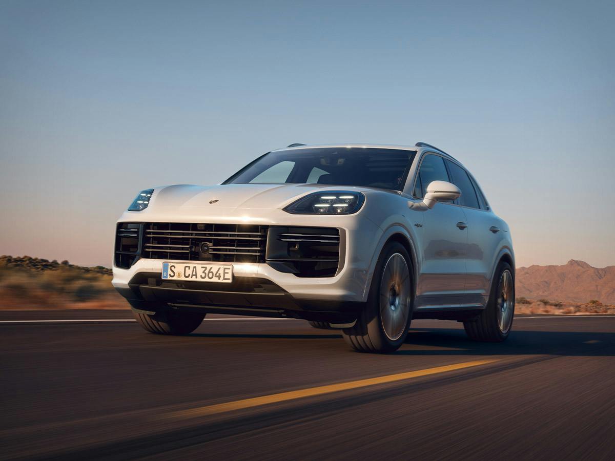 A front shot of a white Porsche Cayenne driving down an empty road.