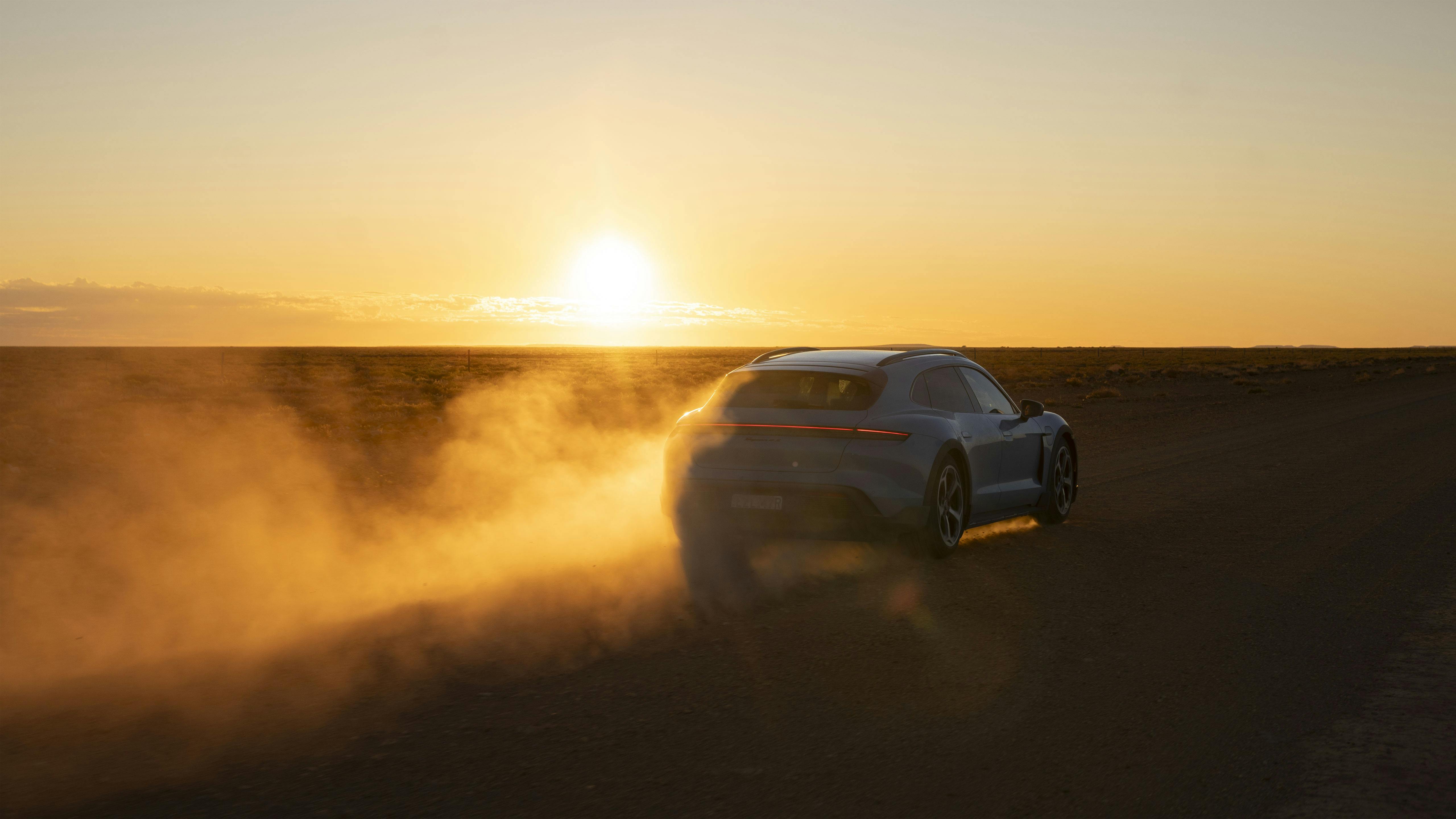 Porsche Taycan Cross Turismo driving at sunset through dusty Outback