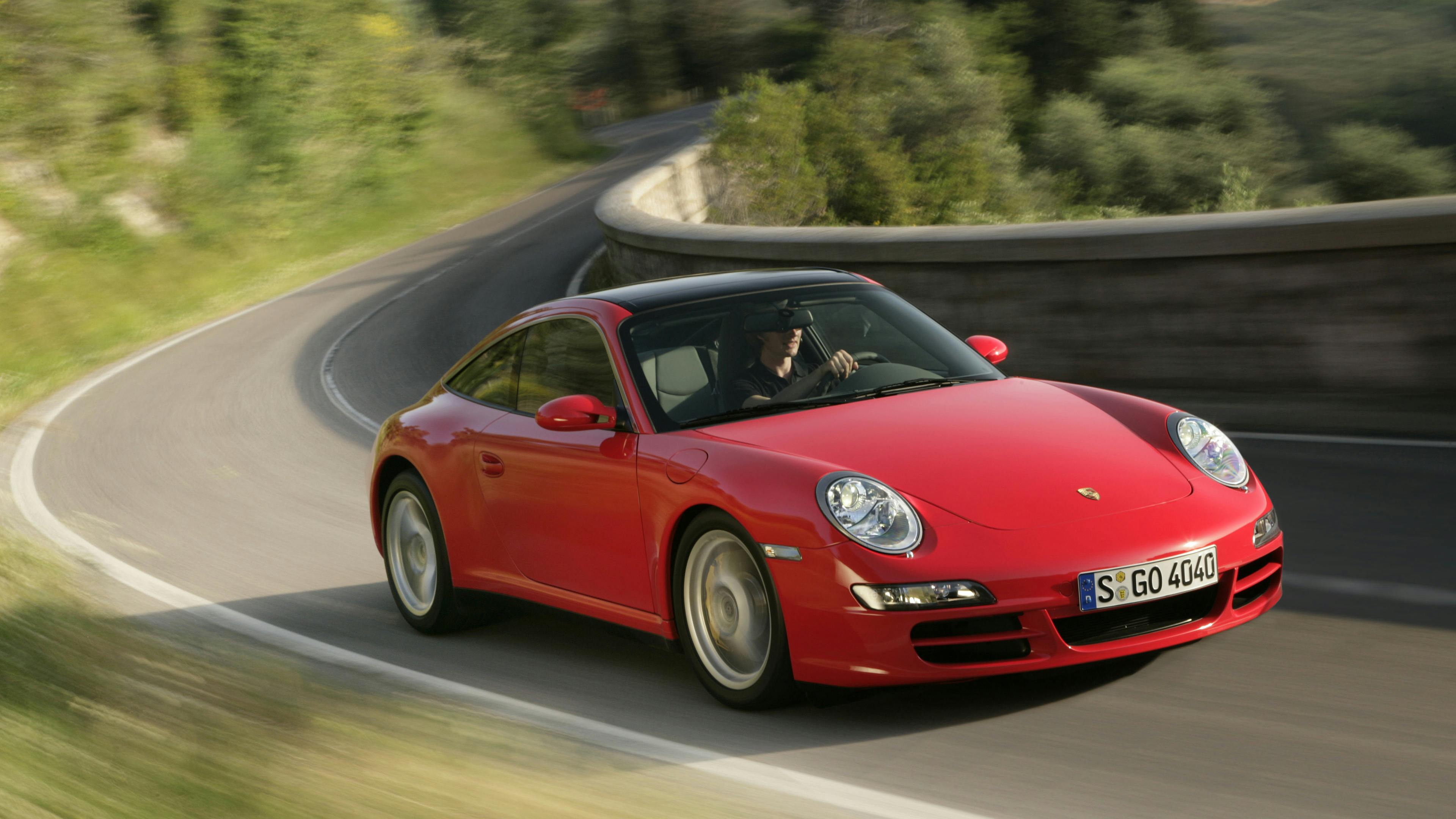 Red 911 Targa 4 of the 997 type on a country road.