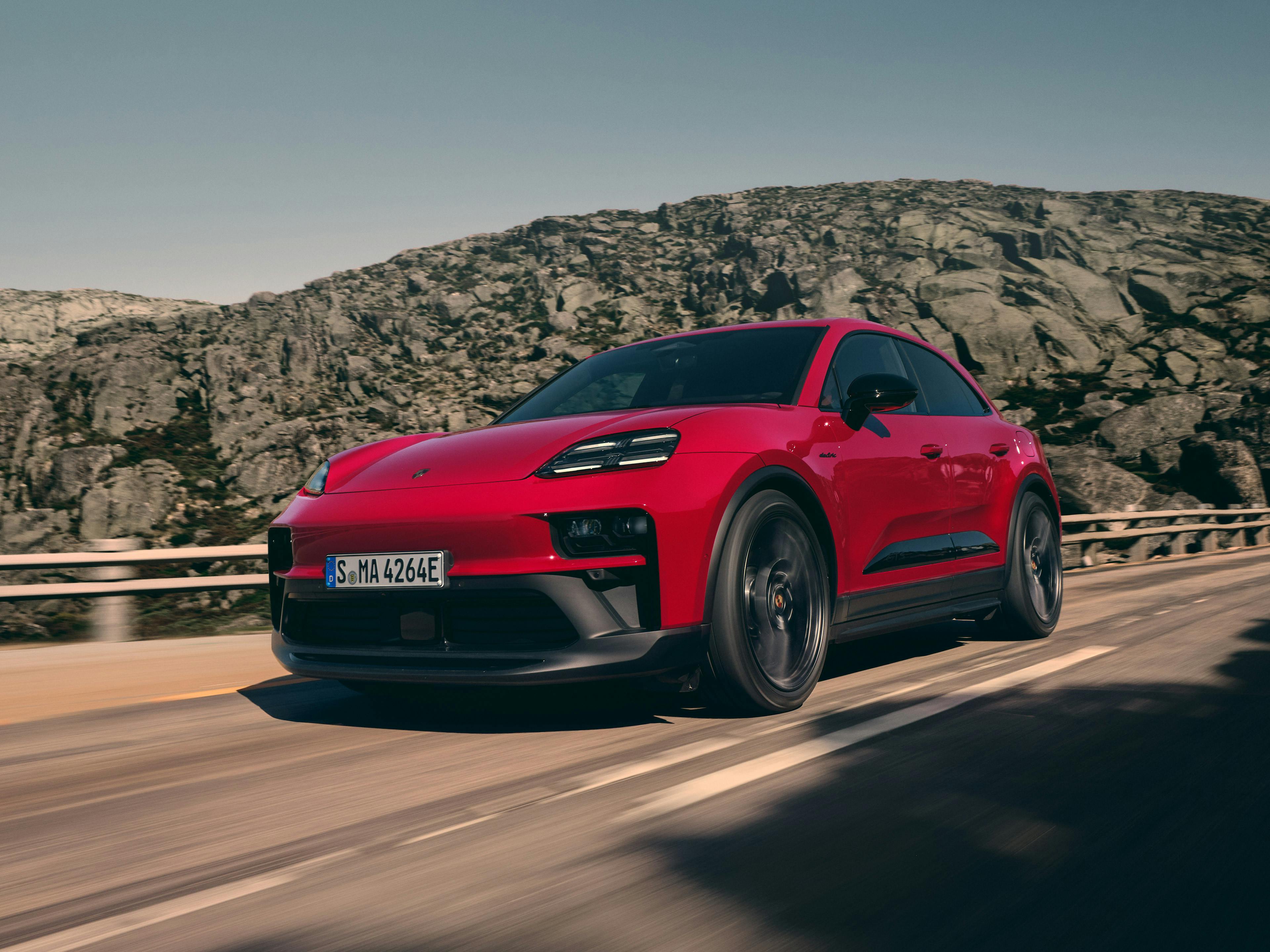The Macan GTS Electric driving along a road in a mountainous region.