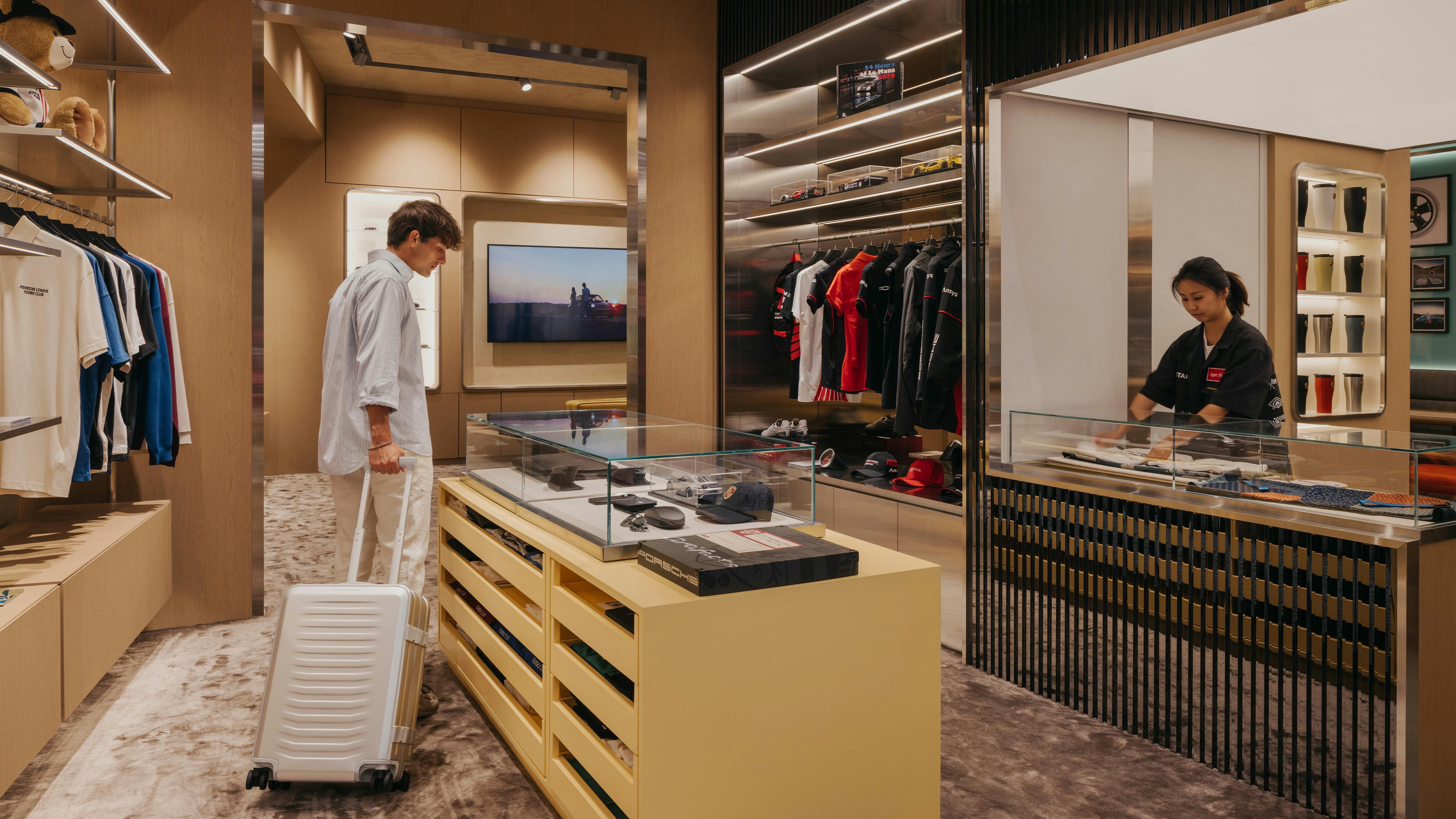 Tourist exploring Porsche Lifestyle Products, luggage in hand.