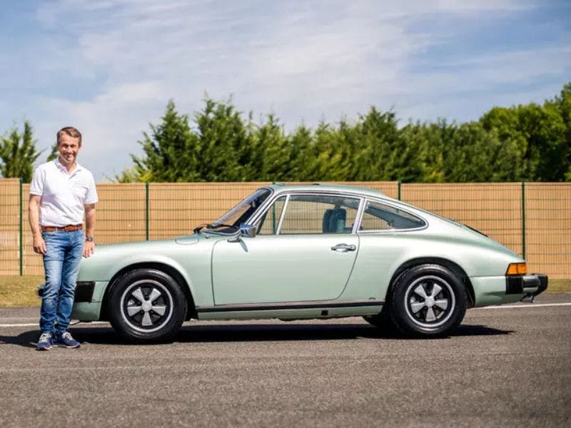 Le participant se tient à côté du véhicule gagnant dans la catégorie restauration complète, une Porsche 911 Speedster 3.2l.