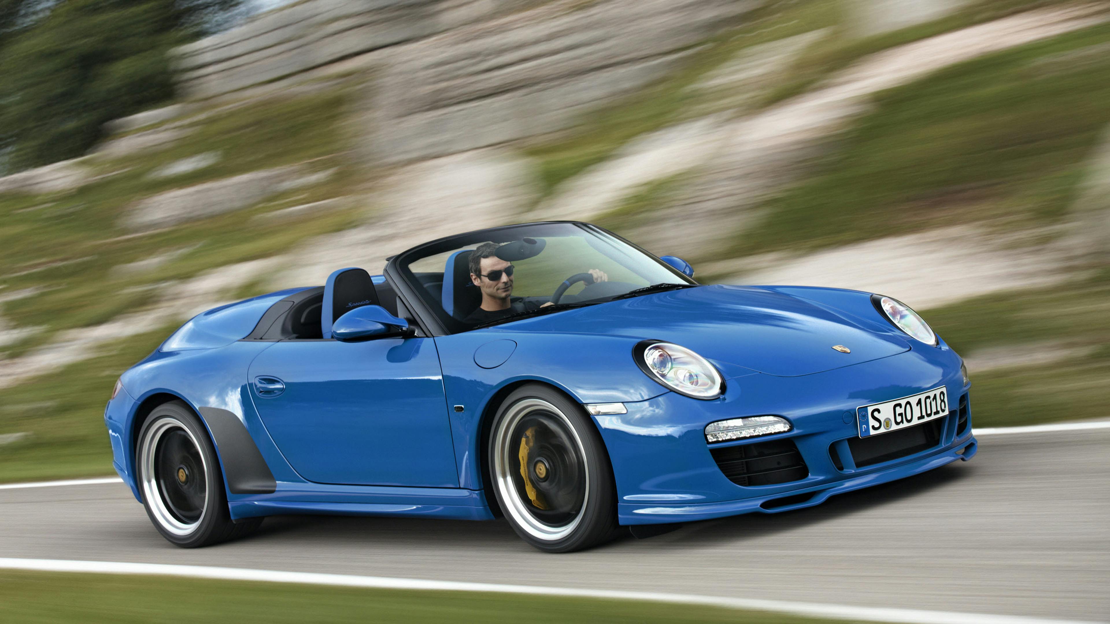 Driving blue 911 Speedster type 997 on a mountain road.