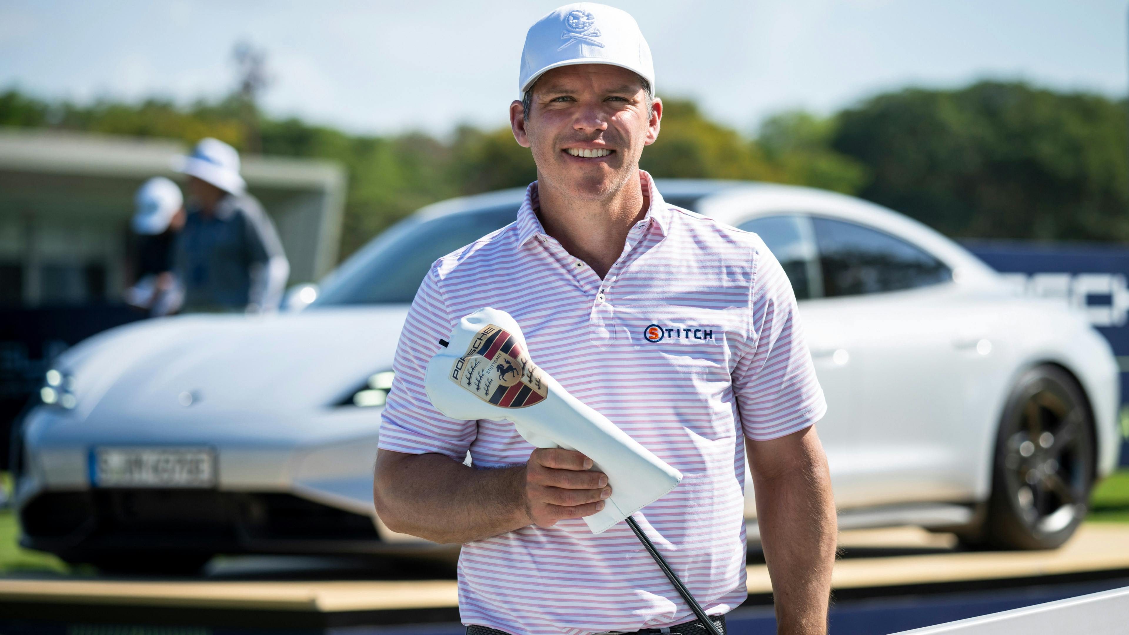 Paul Casey steht vor einem Porsche Taycan