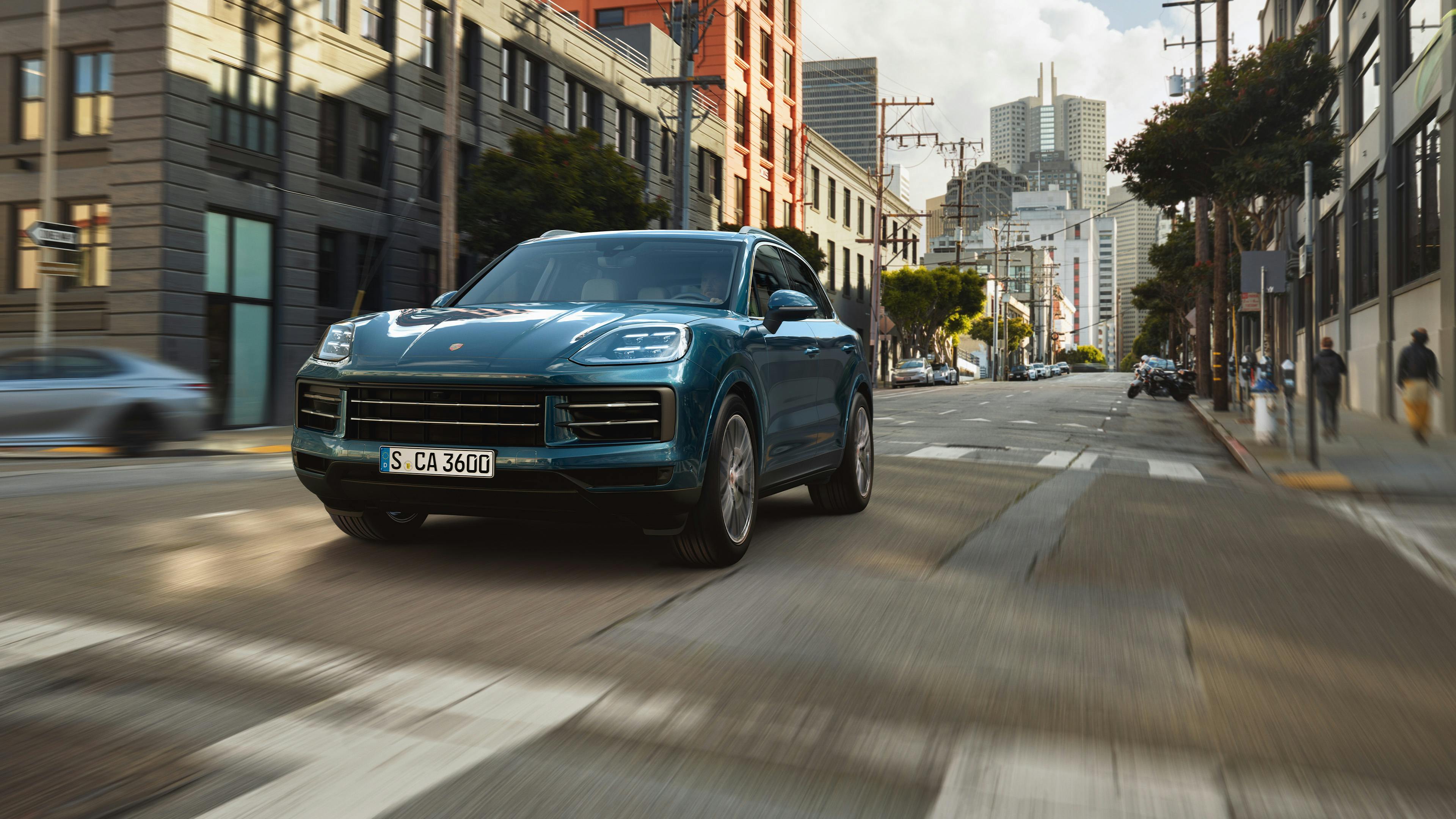 Ein blauer Porsche Cayenne fährt durch eine Stadtstraße.