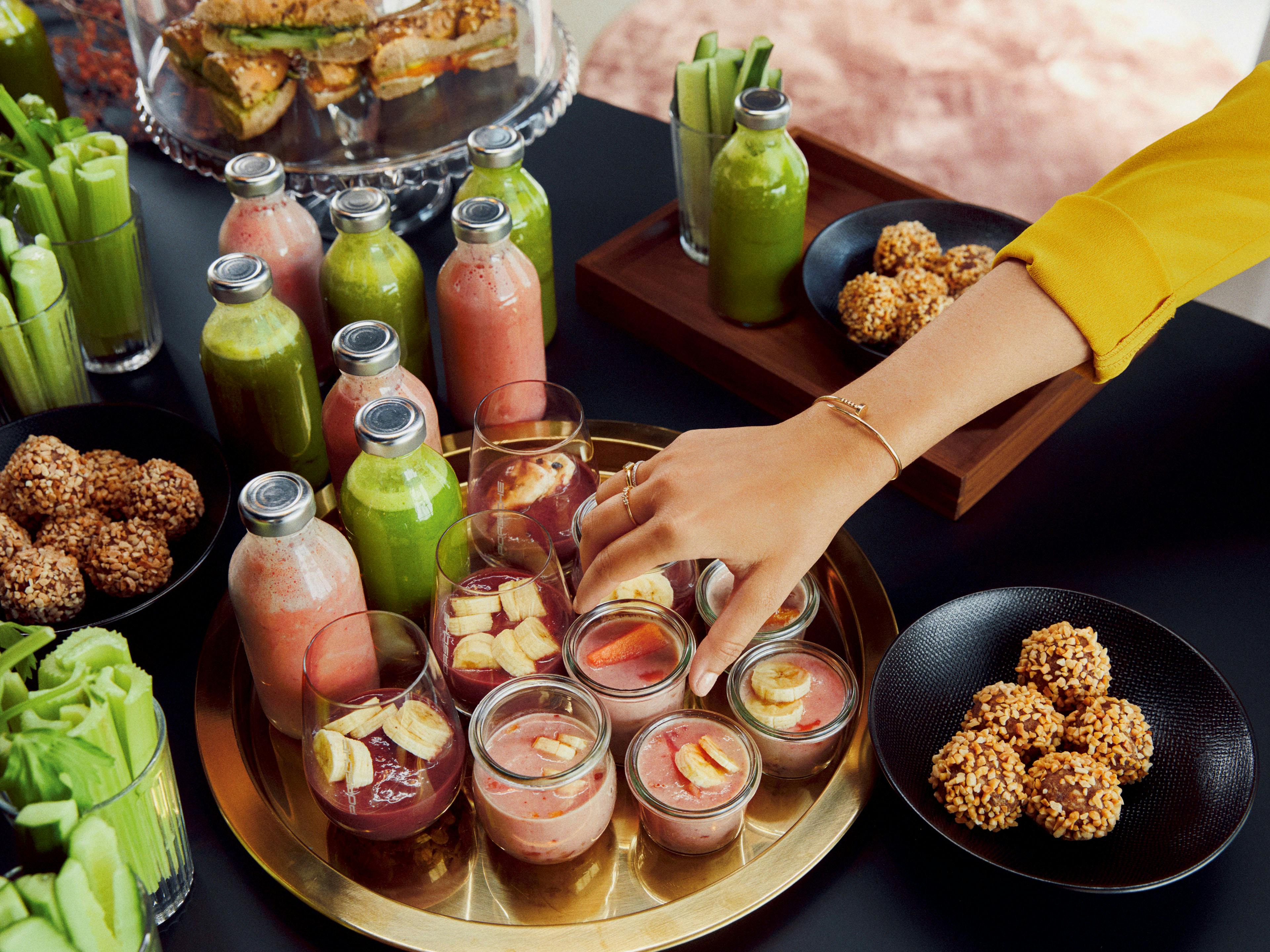 Verschiedene Speisen, Fingerfood, rote und grüne Smoothies auf einem Tablet.