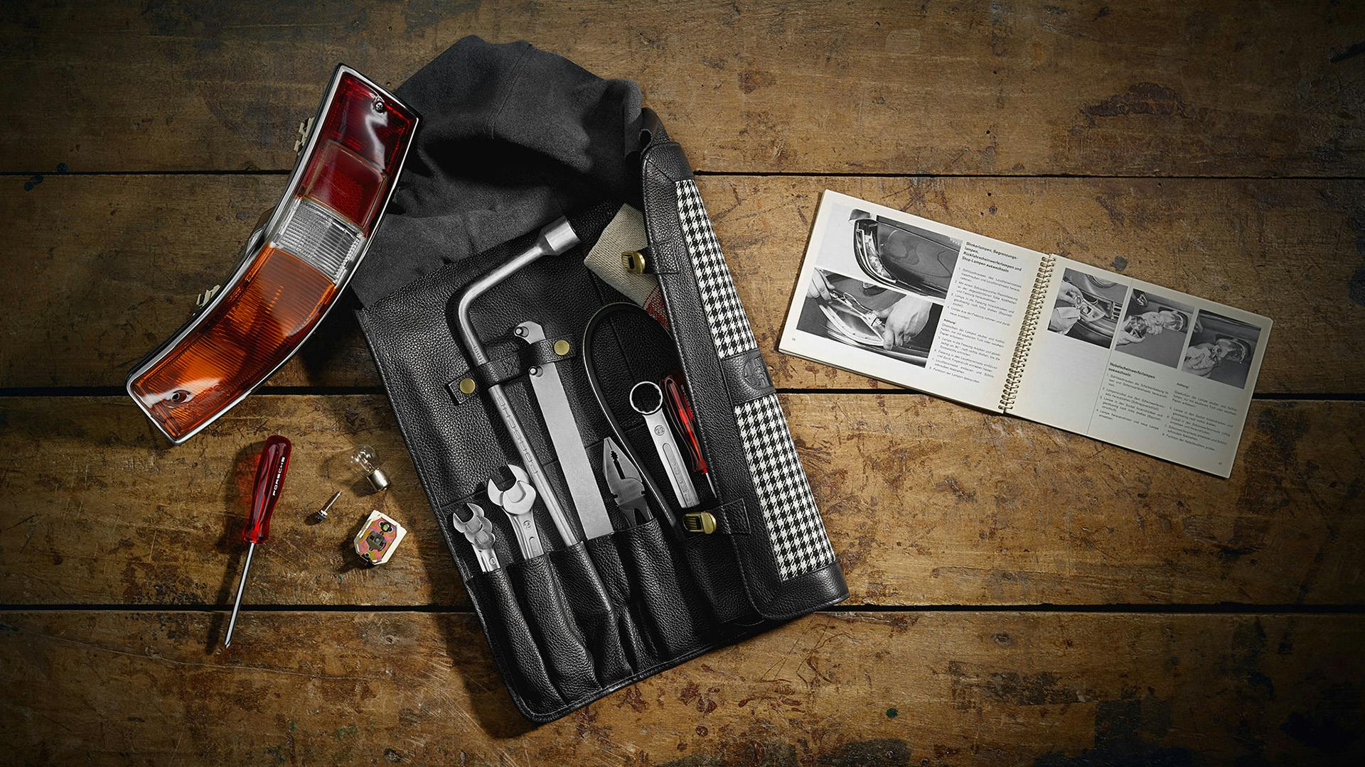 Various spare parts and accessories for classic cars lie on a wooden surface.