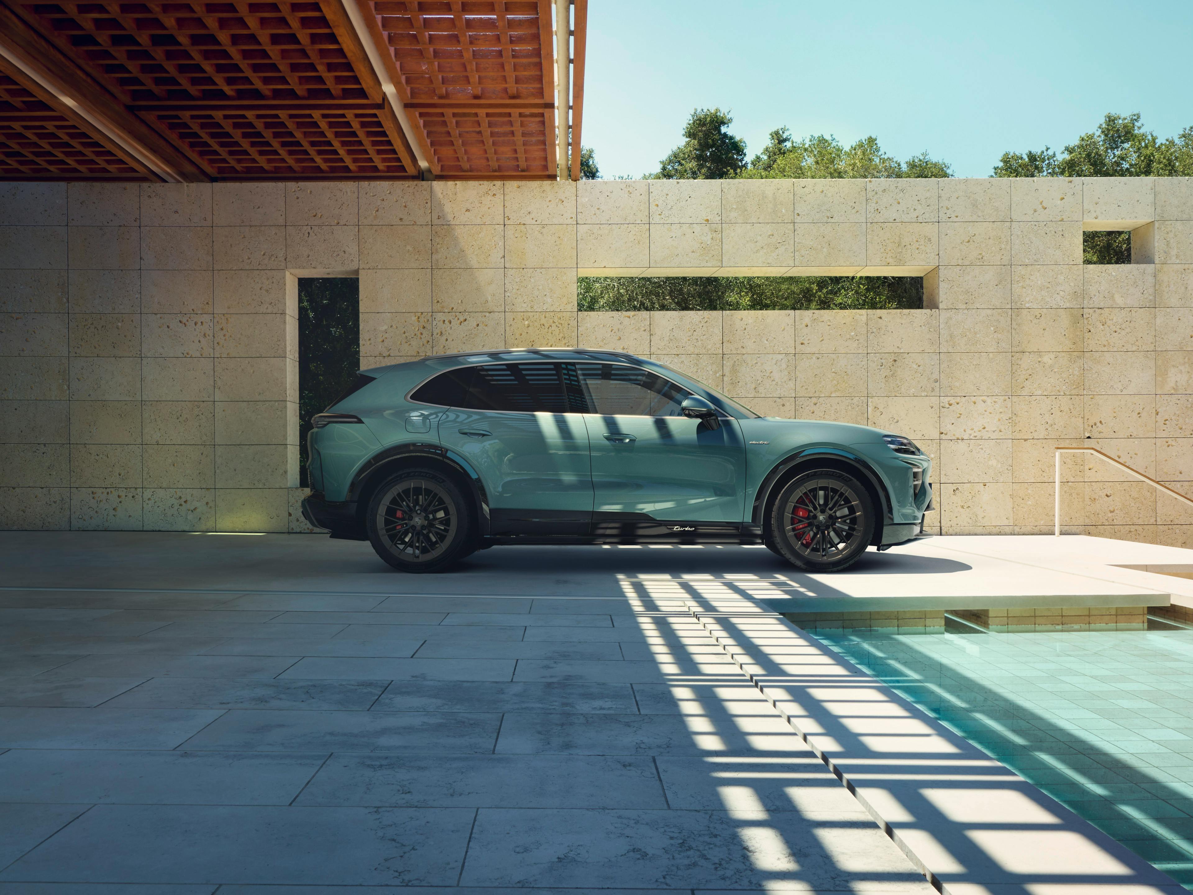 The Cayenne Turbo Electric SUV parked in a vibrant, modern environment, with a pool nearby.