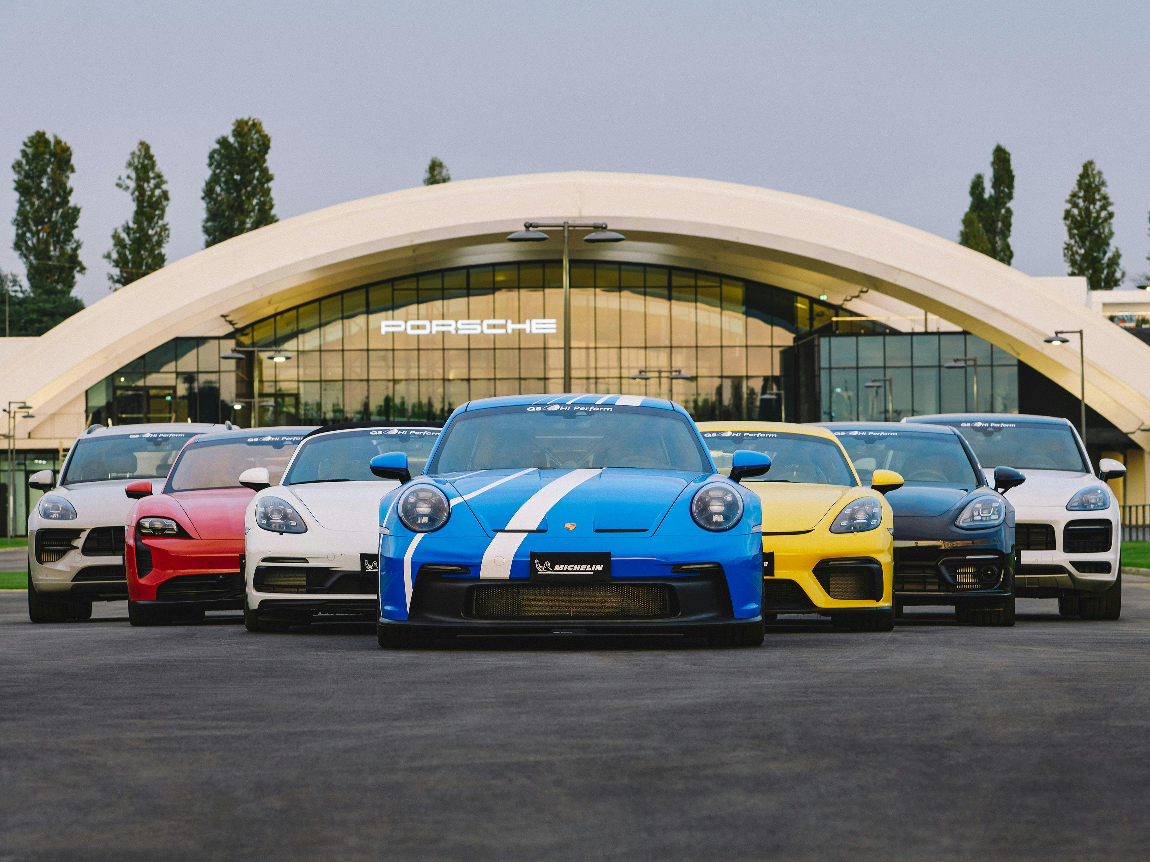 Siete vehículos Porsche en formación frente al Porsche Experience Center Franciacorta.