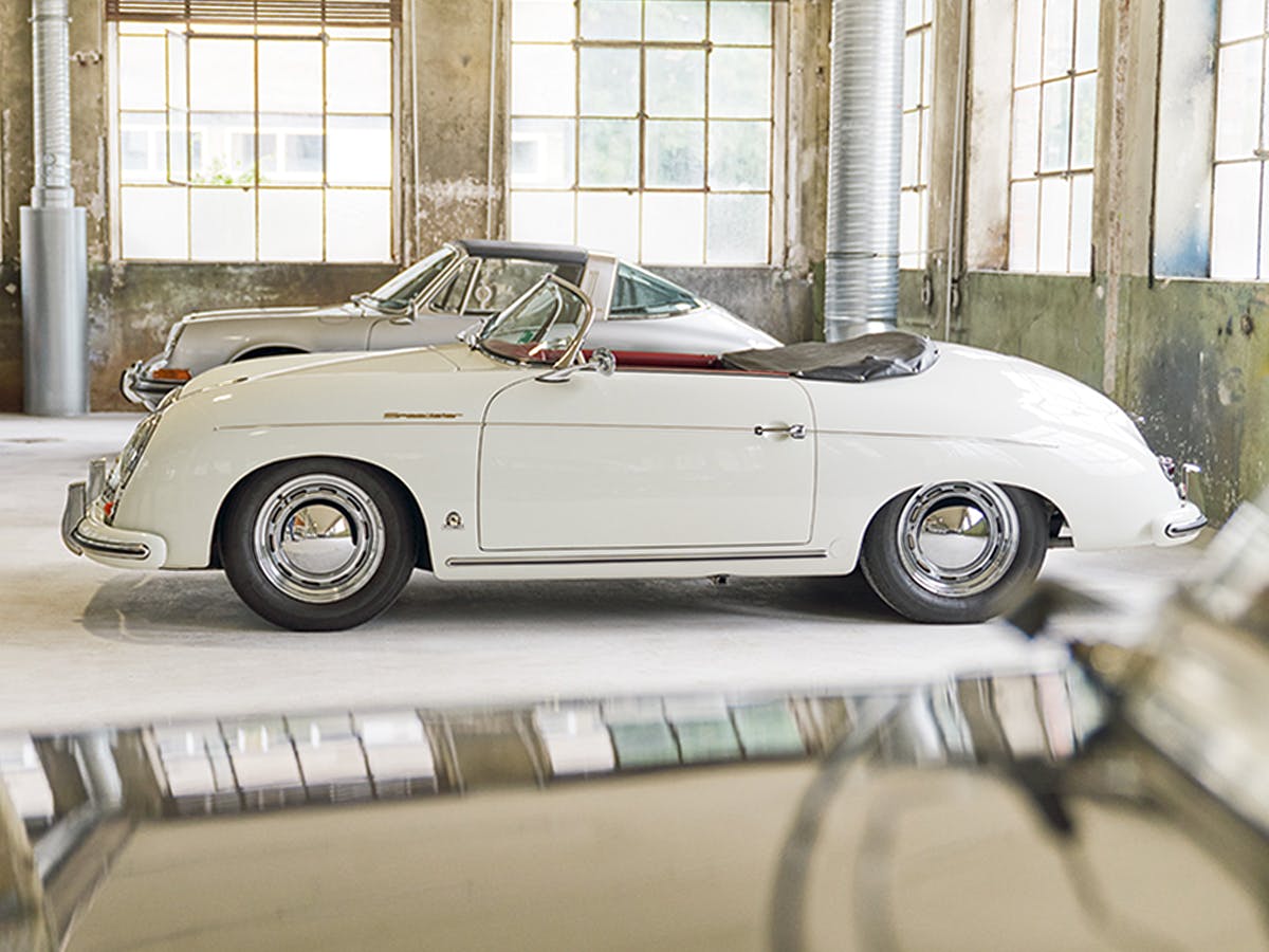 Several classic Porsche models are parked in a bright garage.