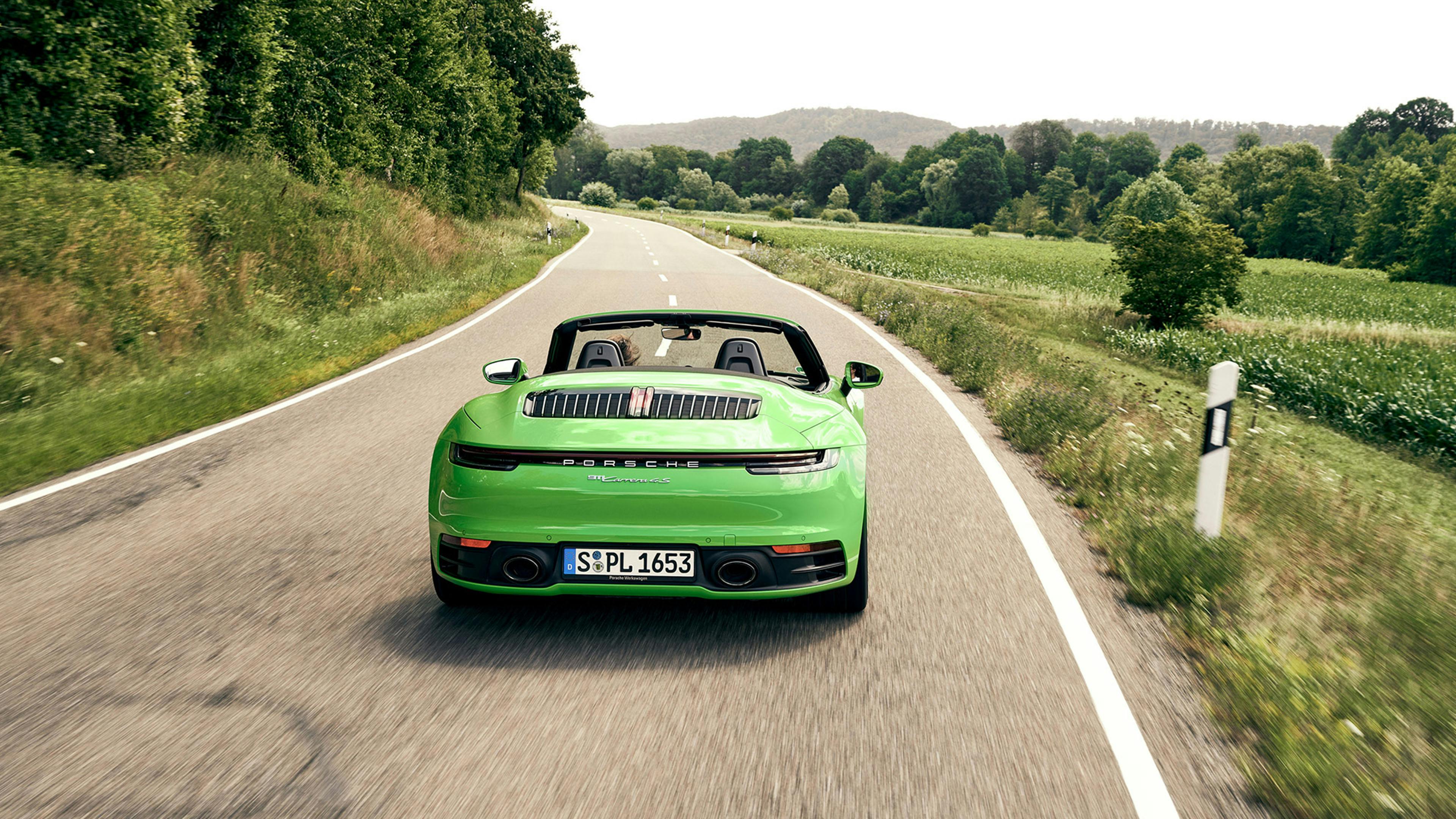 Ein grüner Porsche 911 Carrera 4s auf einer Landstraße mitten in einer grünen Landschaft