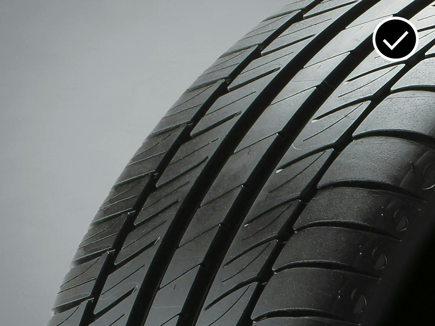 Tire with deep tread lines and a checkmark, indicating good condition.