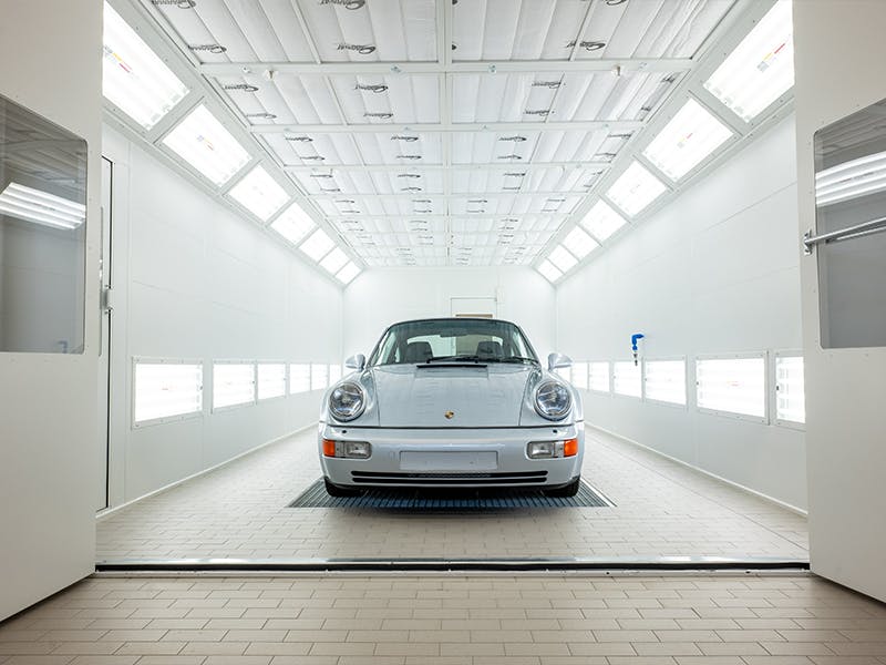 Silver Porsche standing in a white tunnel.