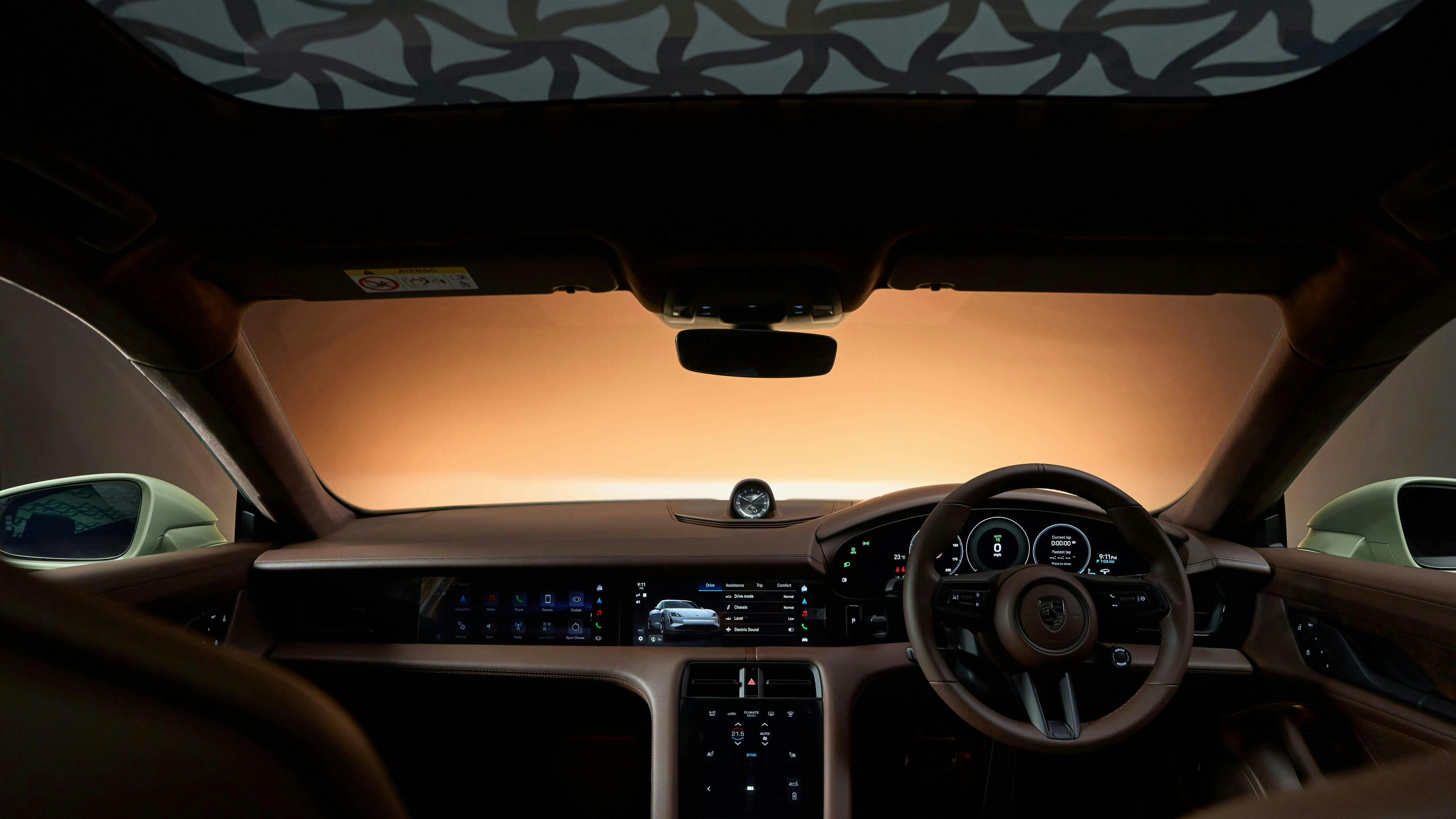 Cabin interior viewed from the rear, showing the dashboard, steering wheel and patterned headliner in warm light.