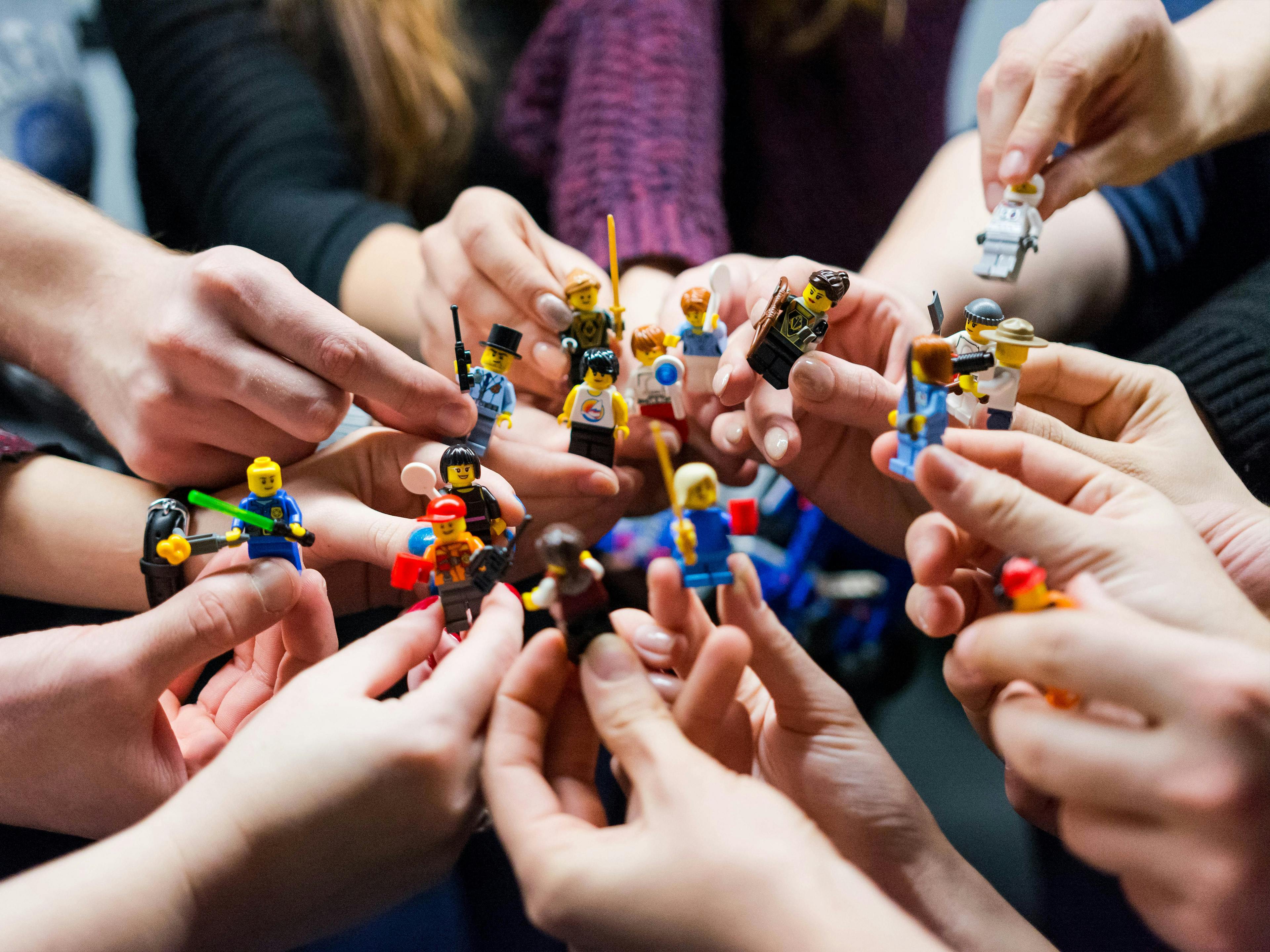 Mehrere Kursteilnehmer zeigen ihre persönlich gestaltenden Lego-Figuren.