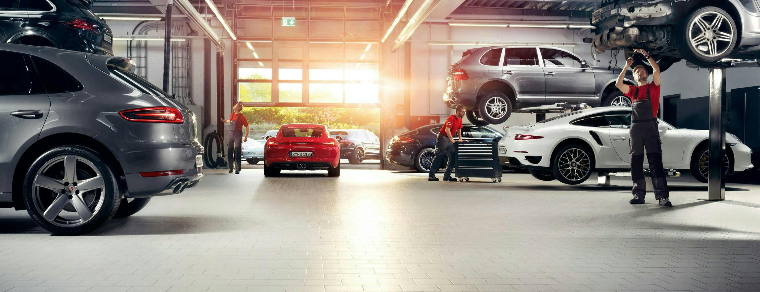 Porsche service with three men working on cars.