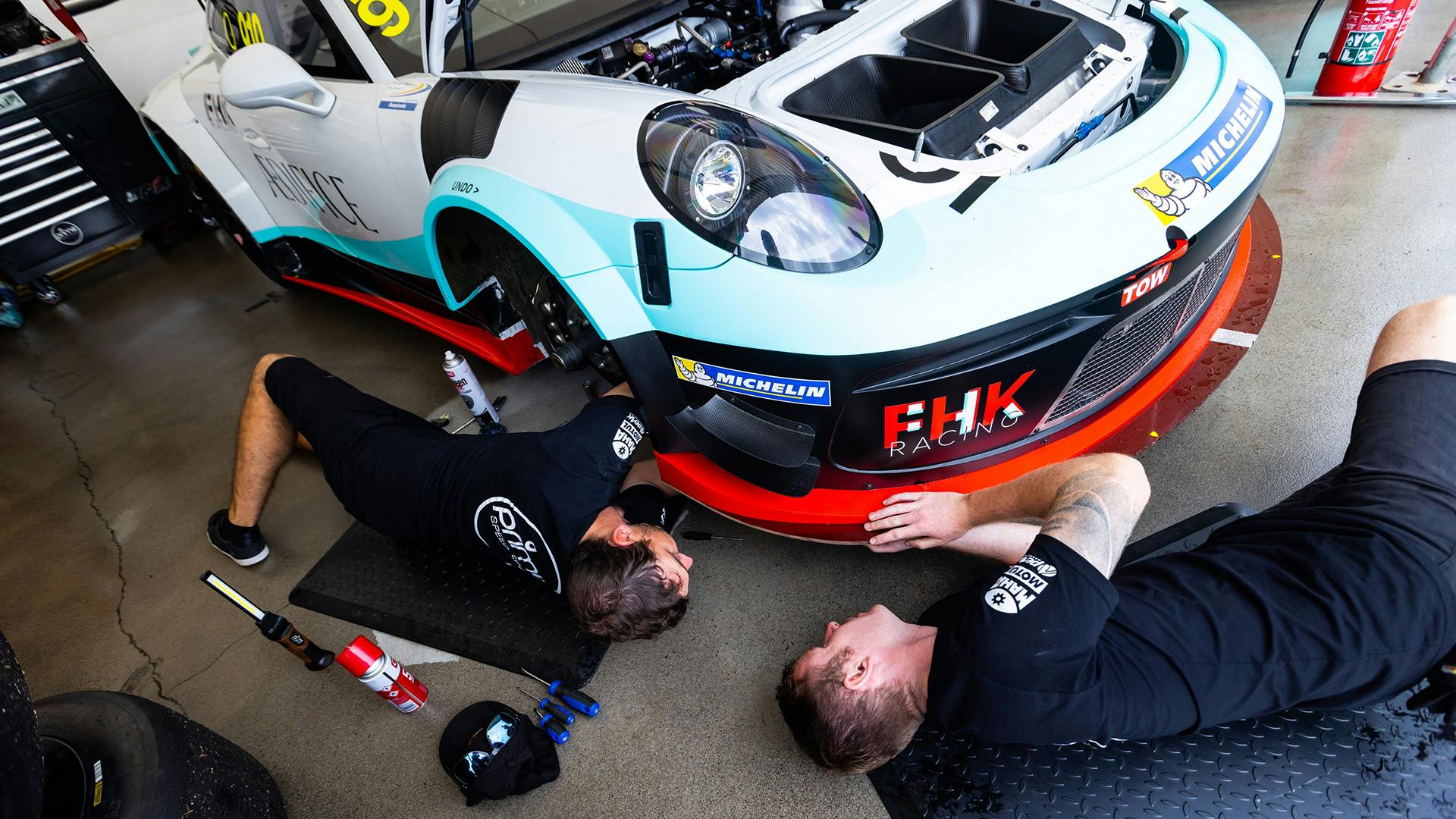 Two mechanics repair a car in the workshop.