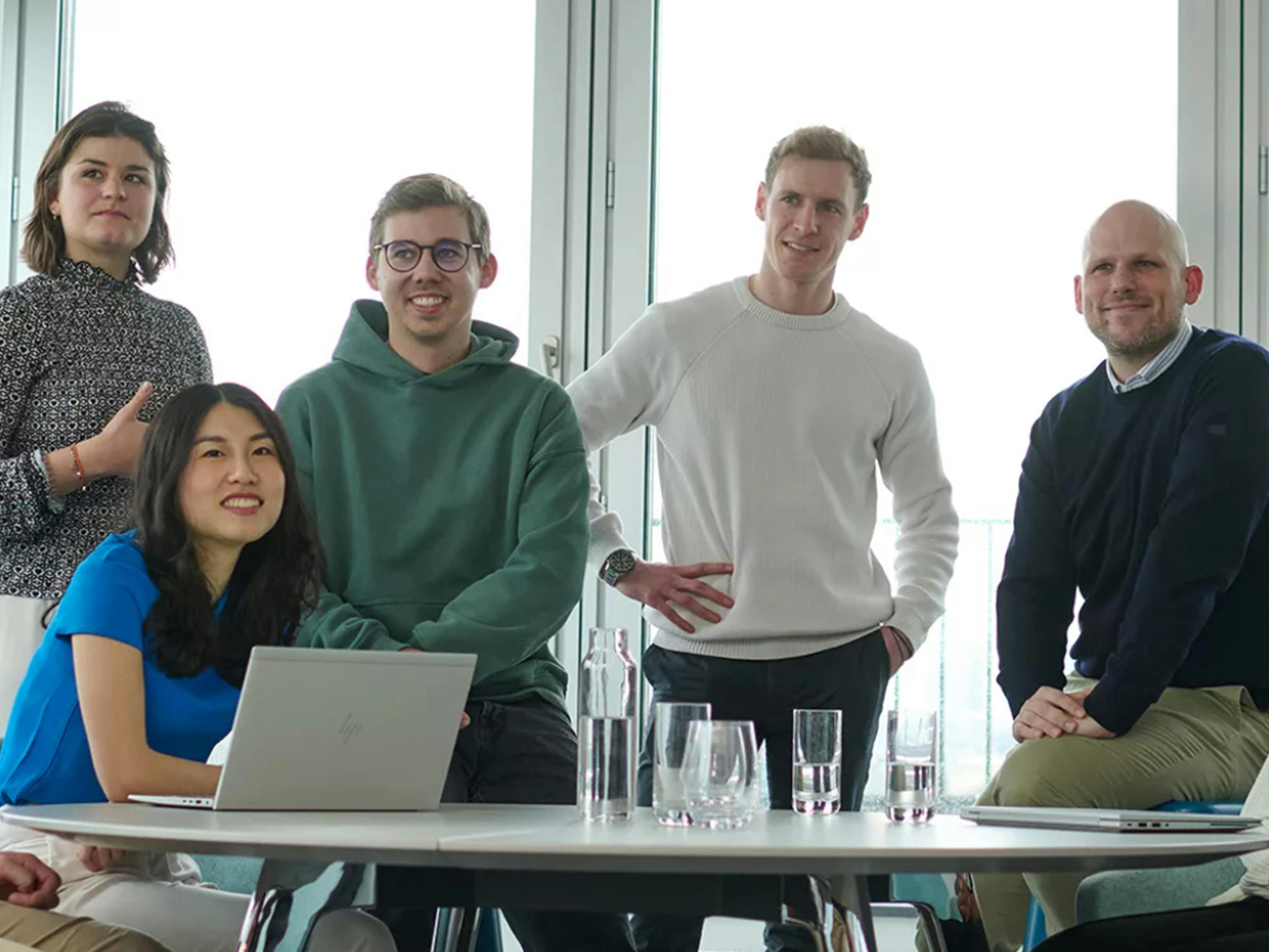 Schwarz-Weiß-Aufnahme: Aufsicht auf mehrere Porsche Mitarbeiterinnen und Mitarbeiter am Tisch mit Laptops.