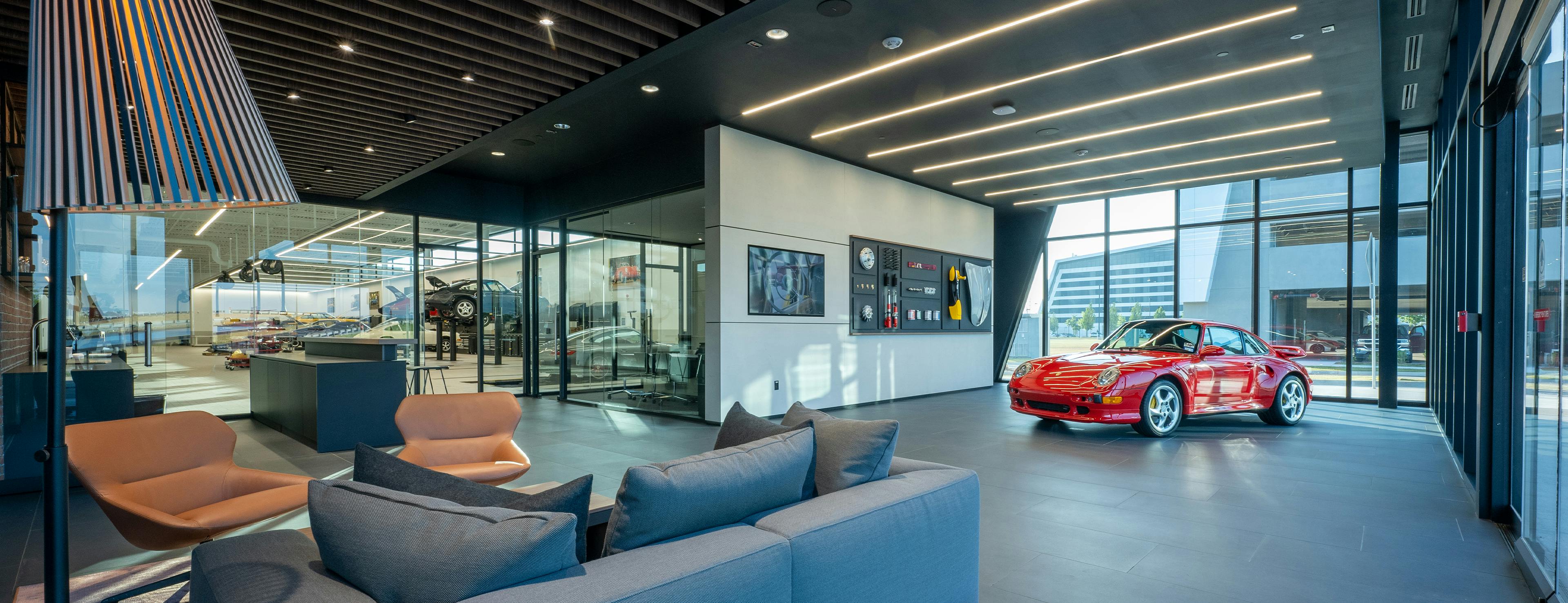 Classic Corner at the Porsche Center Atlanta with a grey seating area and a red Porsche in the background.