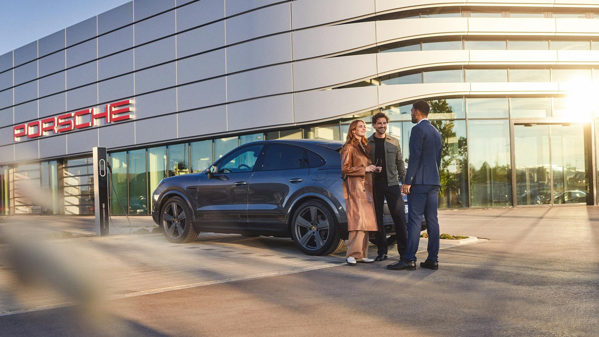 A group of people standing in front of a Porsche centre.