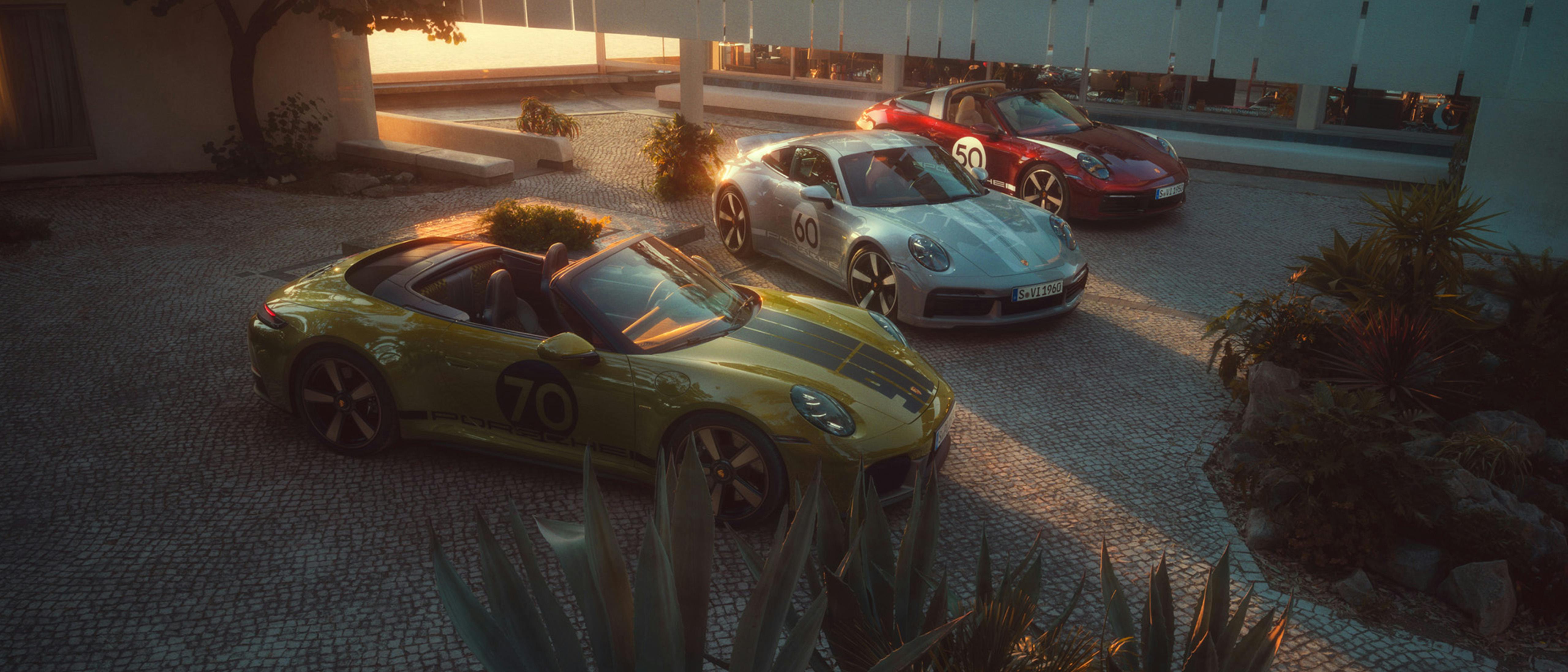 The 911 Spirit 70, 911 Sport Classic and 911 Targa 4S Heritage Design Edition are standing on a paved square at sunset.
