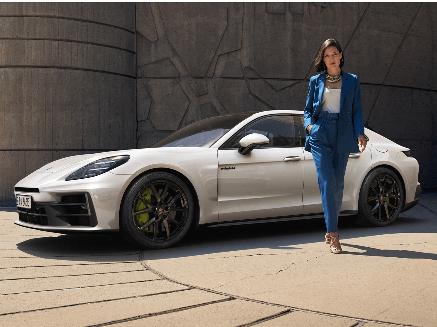 The Panamera 4 E-Hybrid parked near a stone building, with a woman walking away from the car.