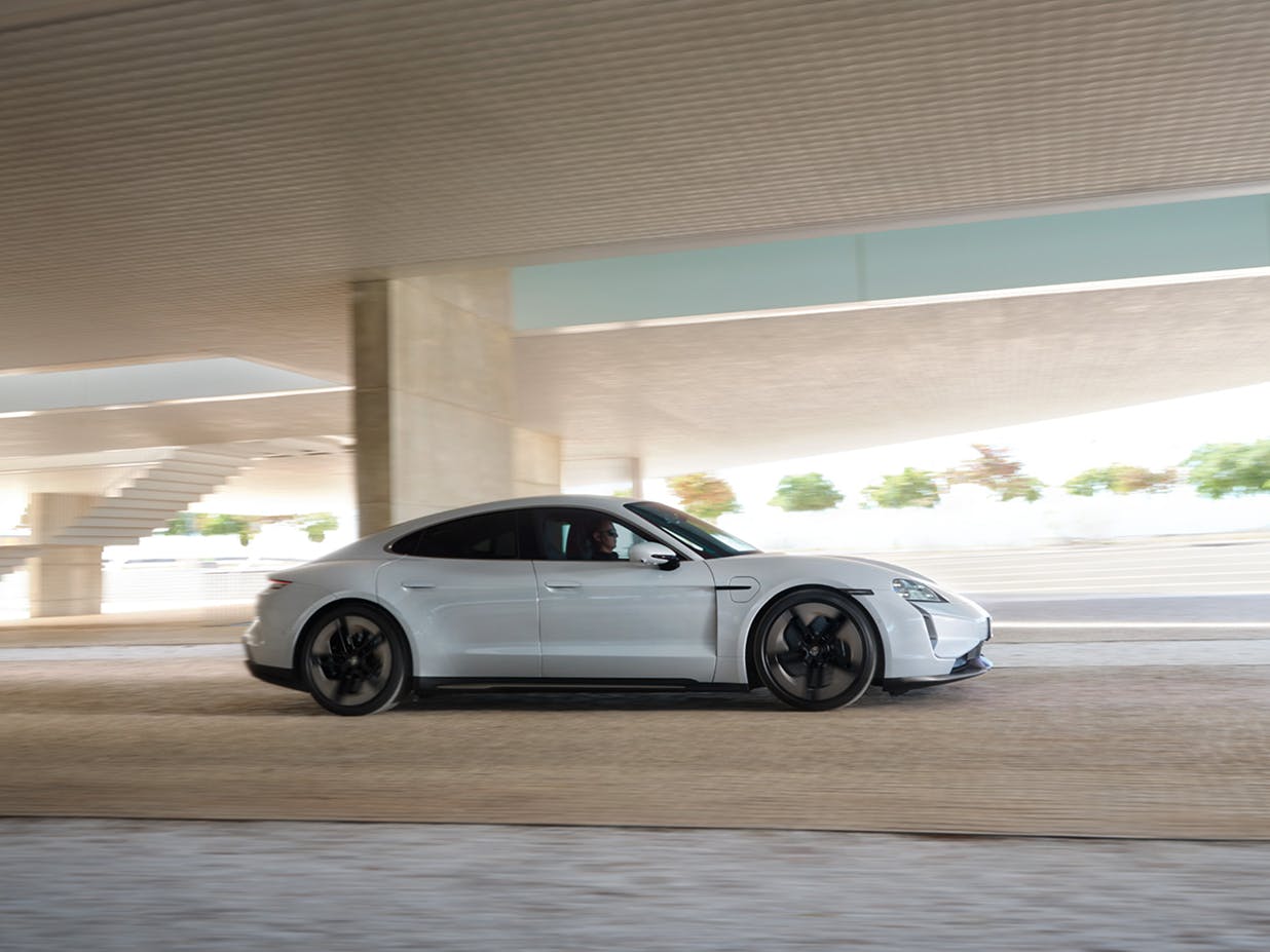 View of the side of a Porsche Taycan driving through a bright underpass.