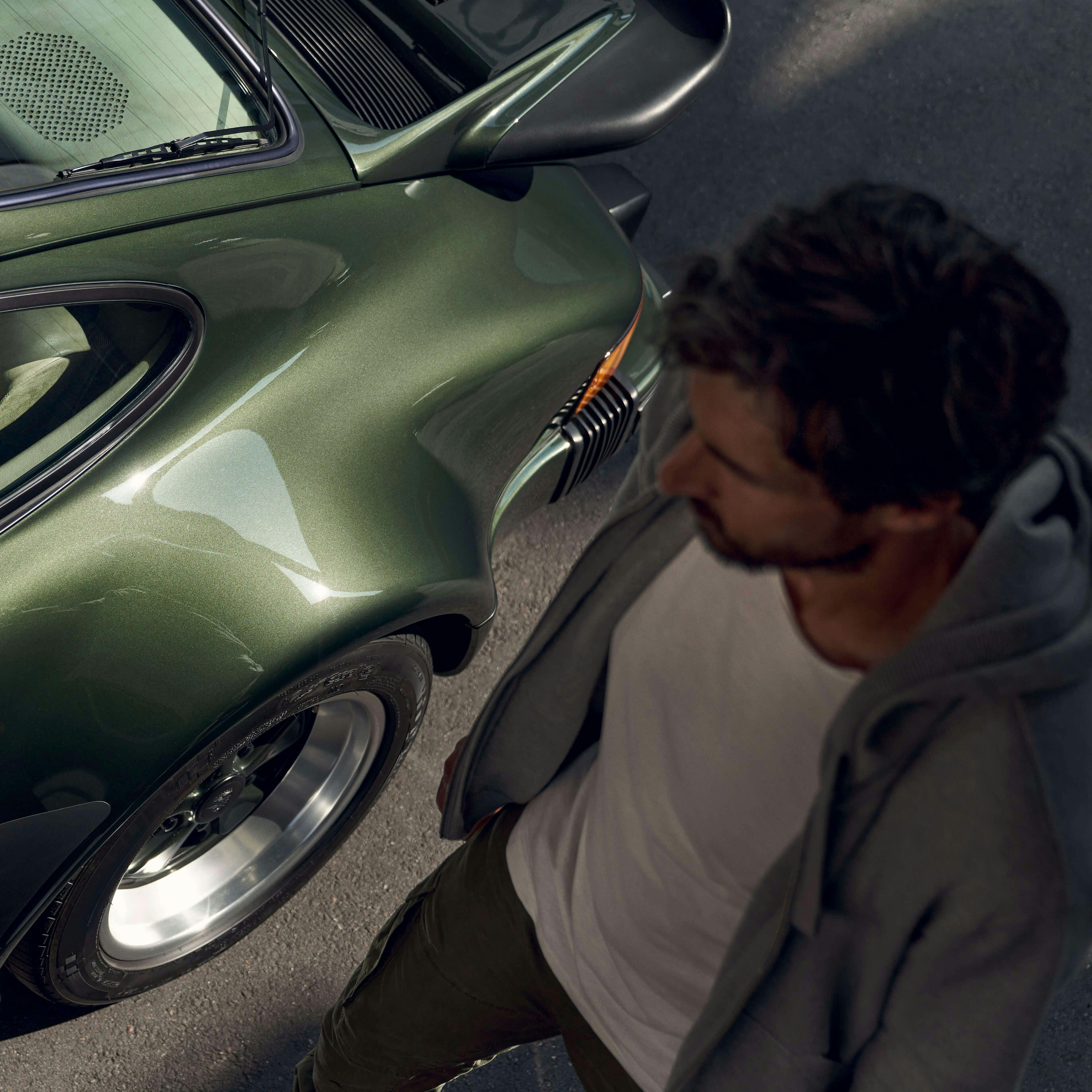 Uomo accanto a una Porsche 911 modello G verde scura