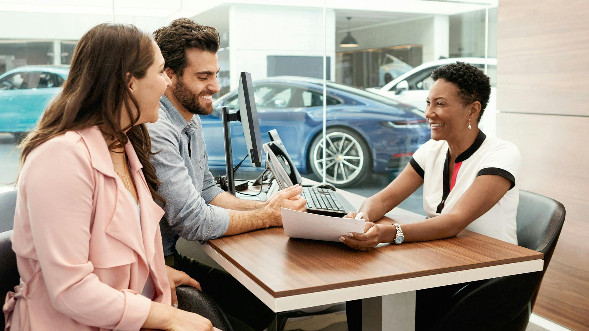 Ein Paar und eine Beraterin während einer Beratung im Porsche Autohaus.