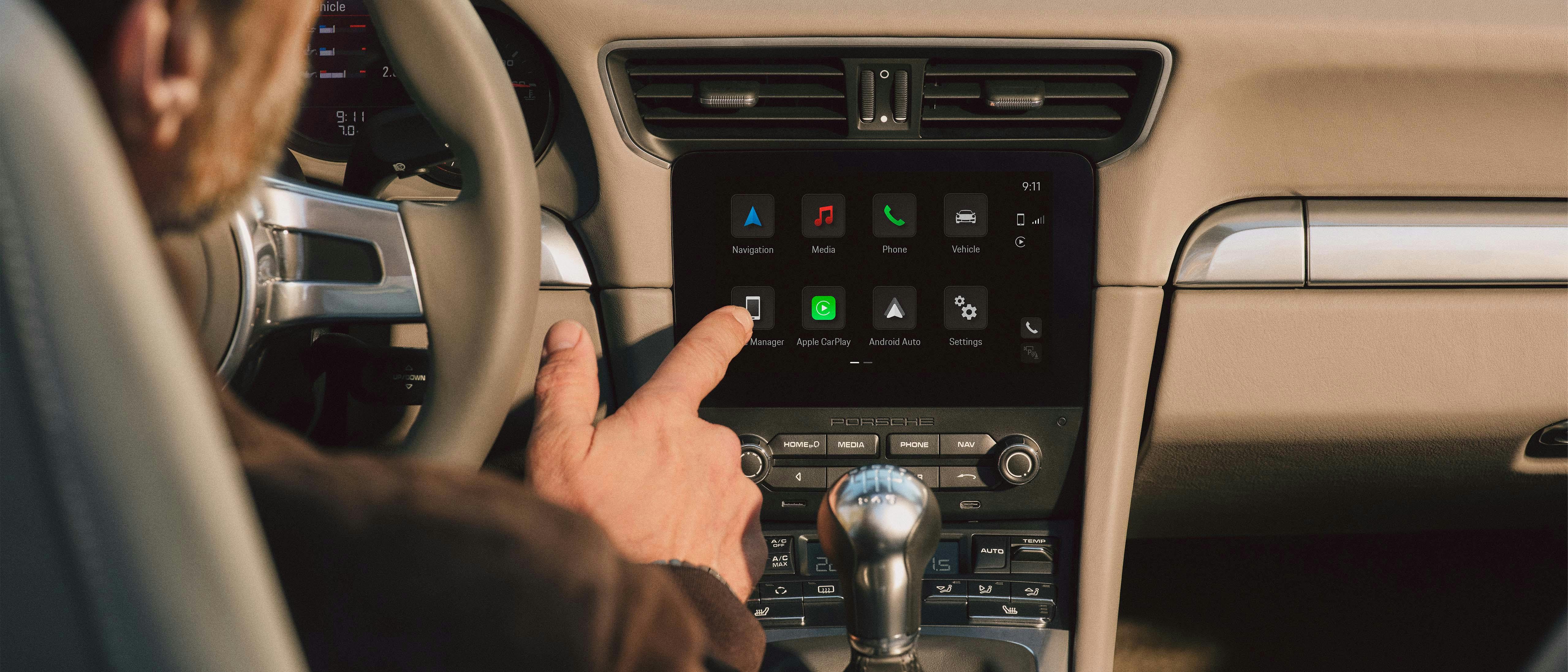 A man is operating the Porsche Classic Communication Management Plus in a Porsche 911 (Type 991).
