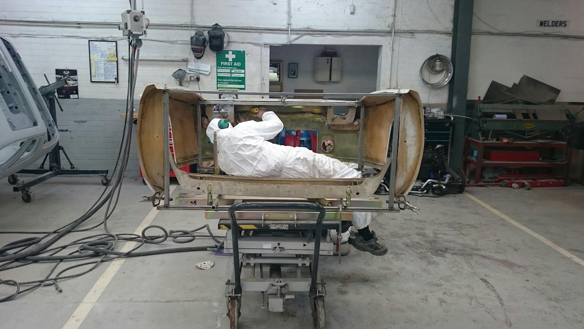 Employee working on the front body of the Porsche 924 GTP doing body work.