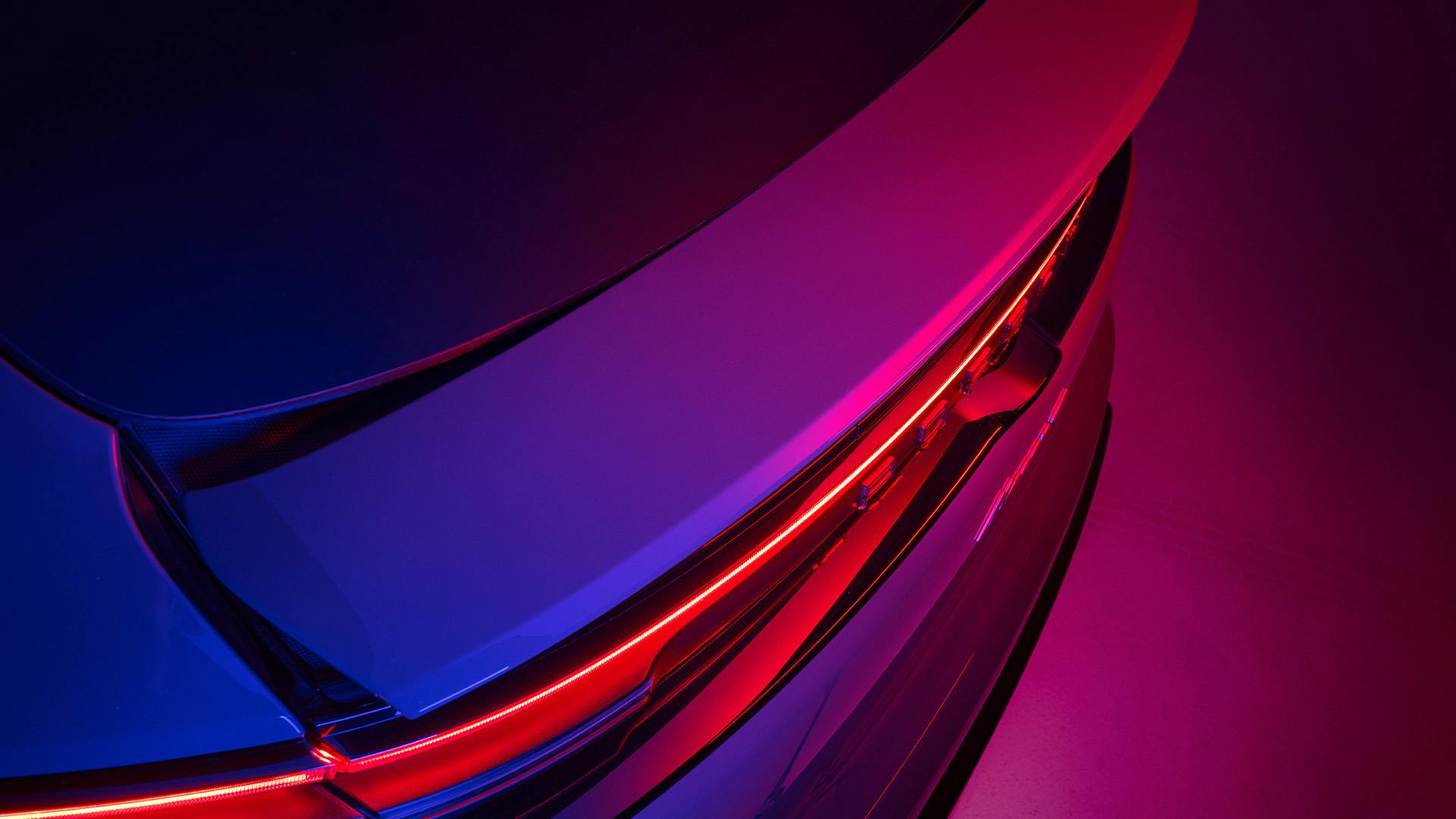 Das Heck eines Porsche Fahrzeugs in blau-pinkem Licht-Setup.