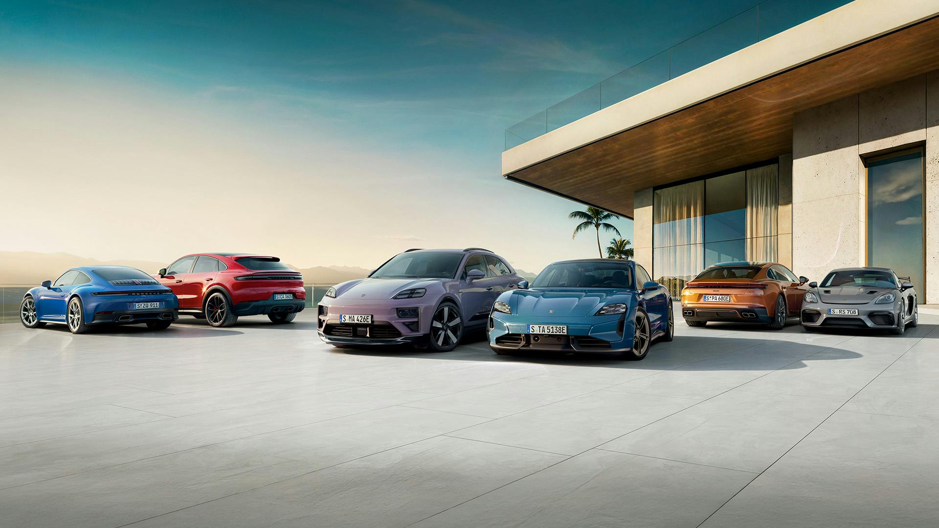 Multiple Porsche models in blue and violet parked in front of modern villa with glass facade, palm trees, and sunset.