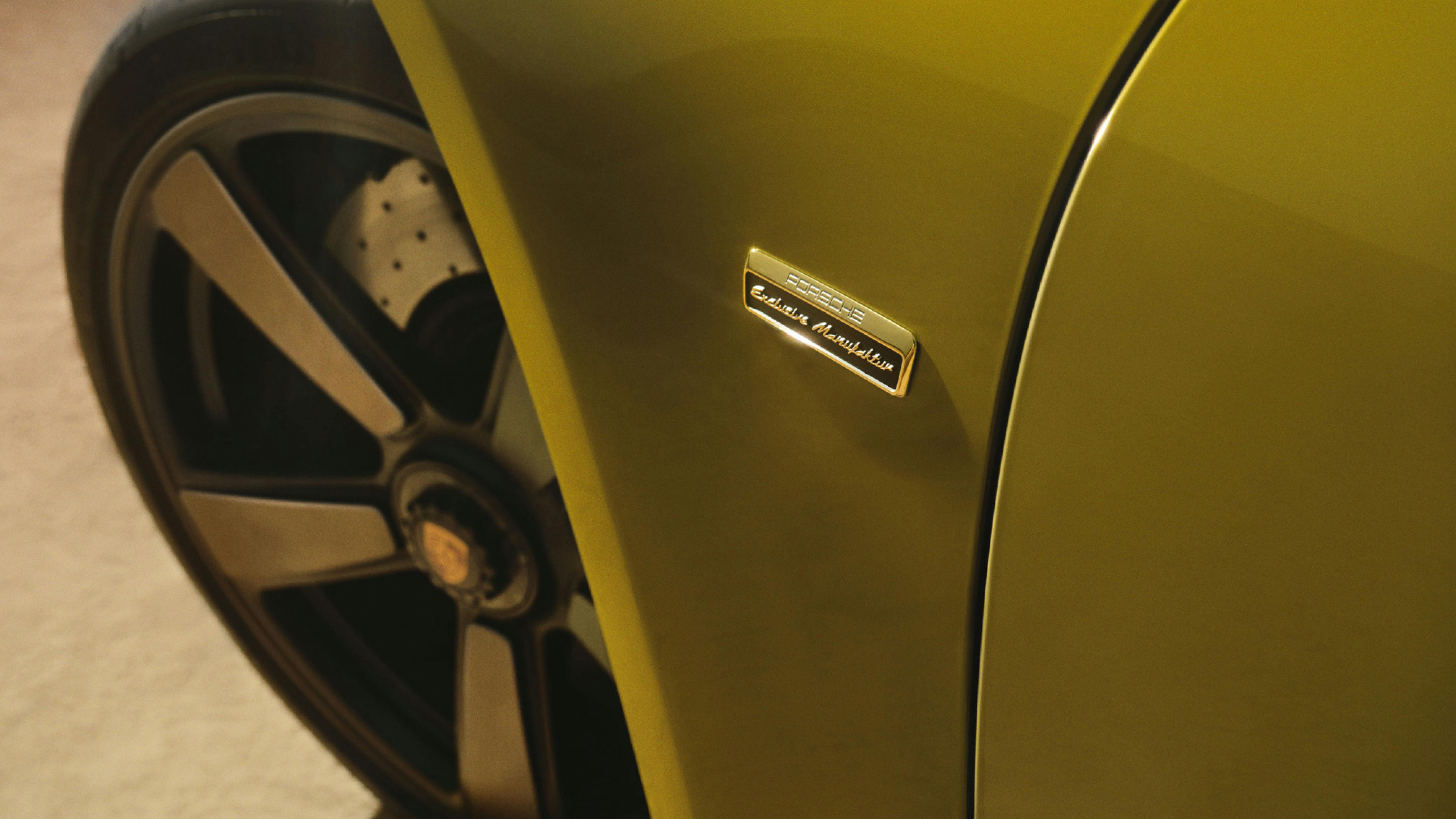 Detalle de la carrocería de un Porsche 911 70 Spirit con el emblema "Porsche Exclusive Manufaktur" y parte de la rueda.