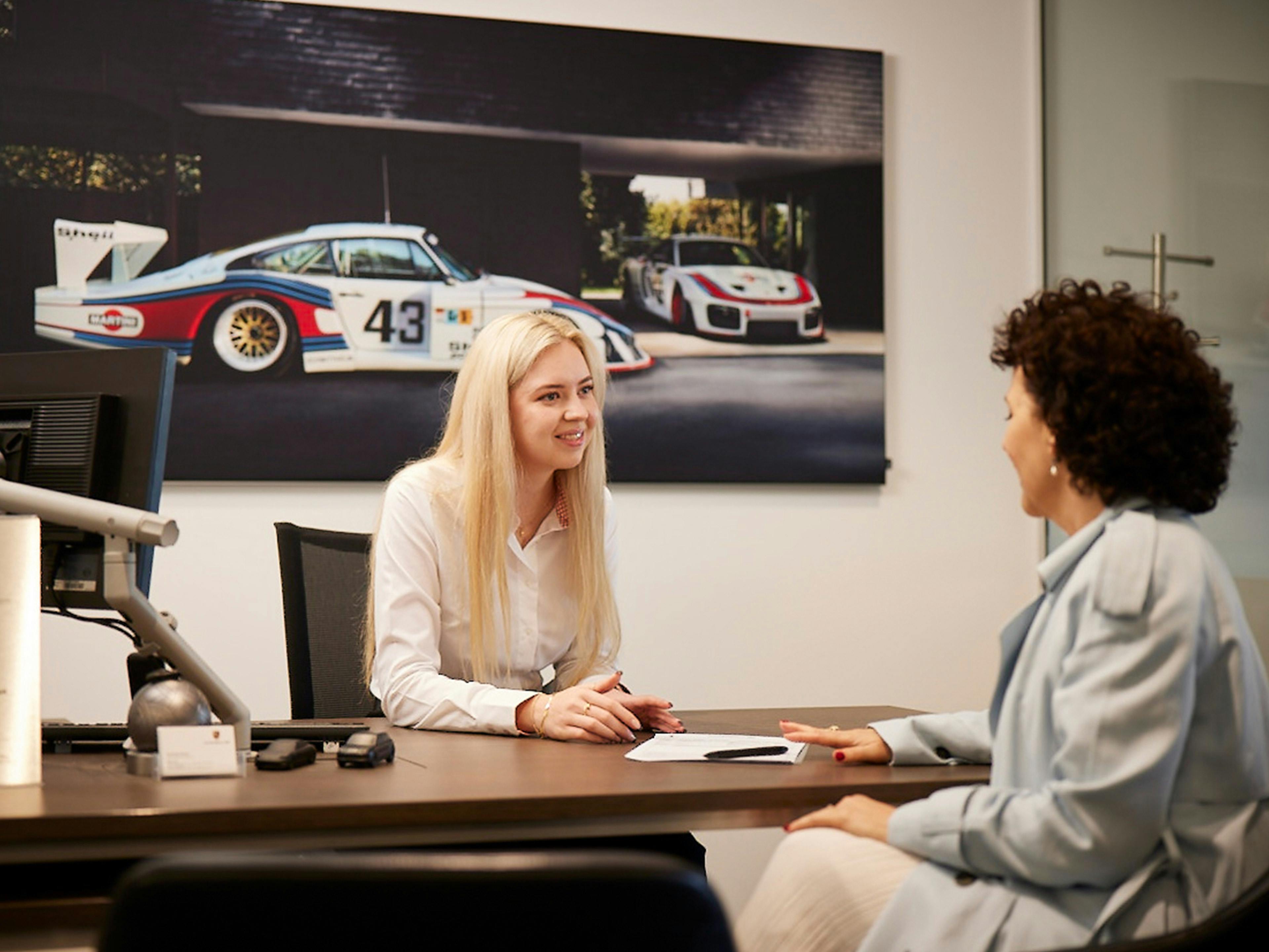 Porsche Service Consultant holding a genuine Porsche part.