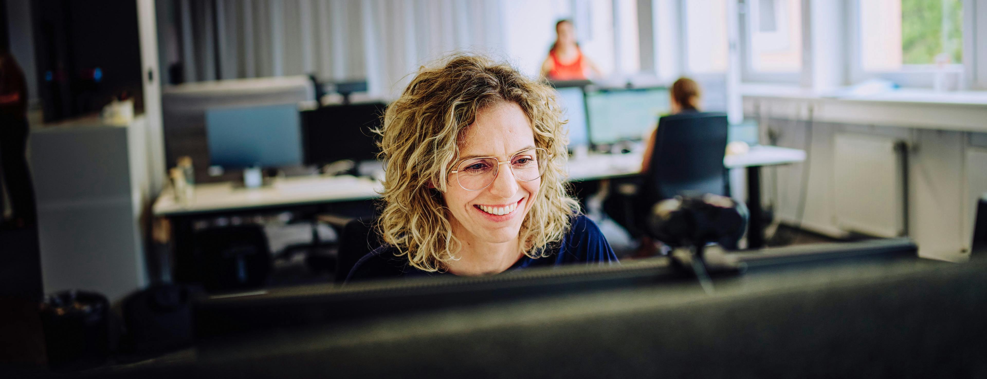 A doctoral student at Porsche smiles at her screen.