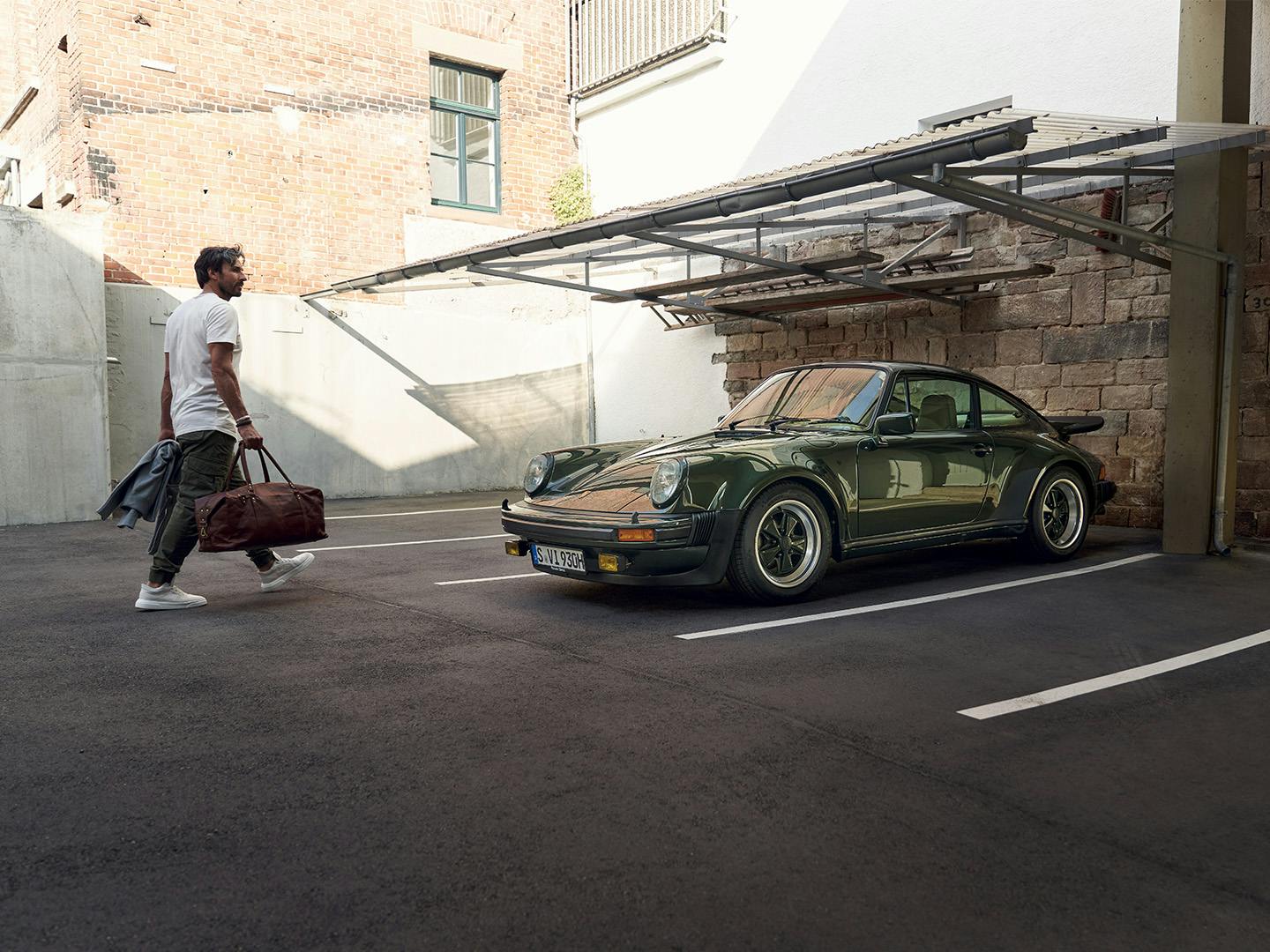 Porsche 911 G-model staat geparkeerd en een man loopt er naartoe.