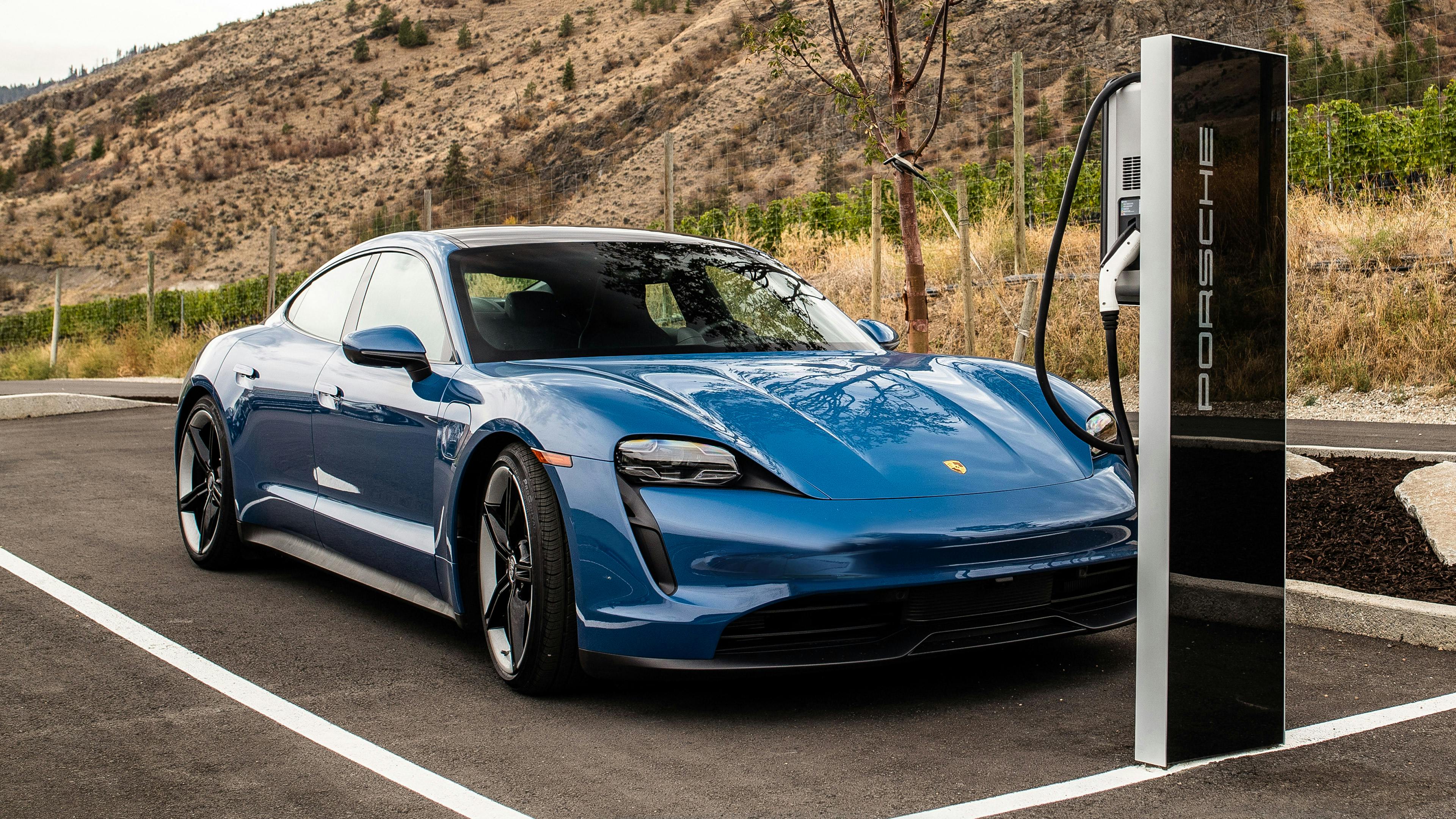 A blue Porsche Taycan recharging at a charging station.